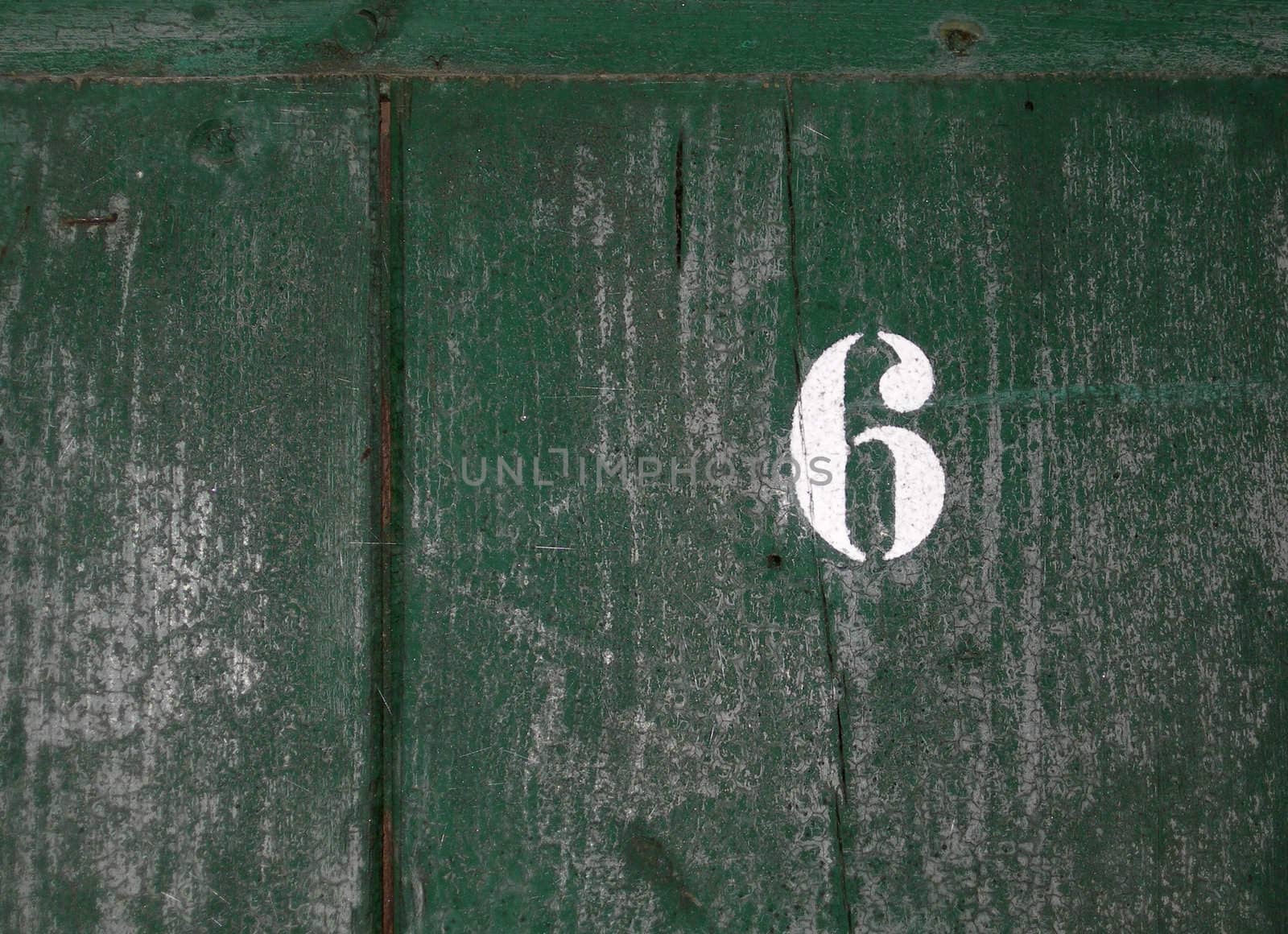 Number 6 written on an old weathered green door