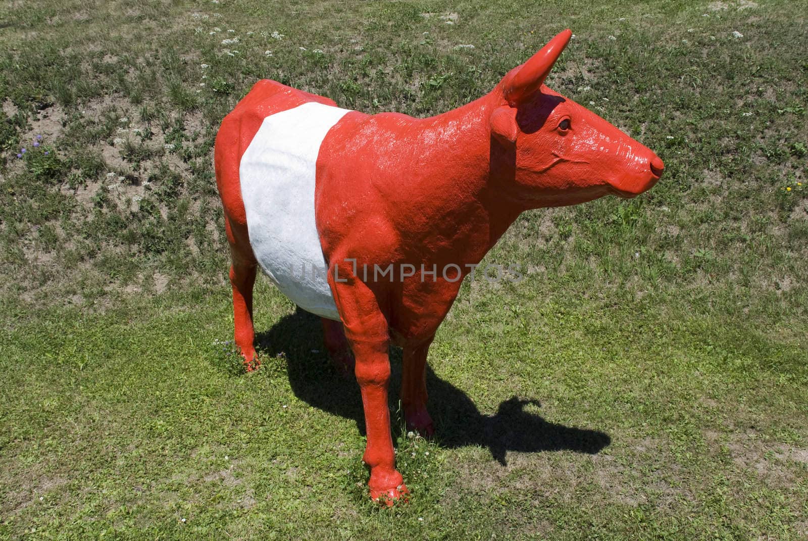 Red plastic cow standing on grass