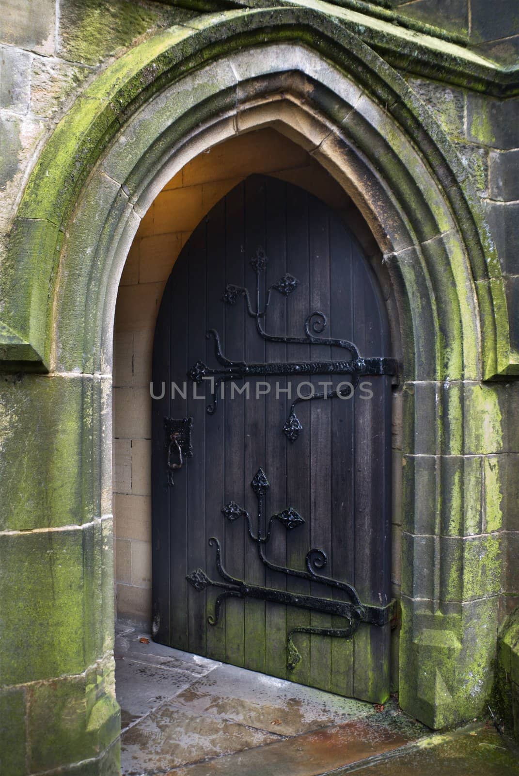 Gothic style church doorway with old iron-hinged door standing open to welcome worshippers