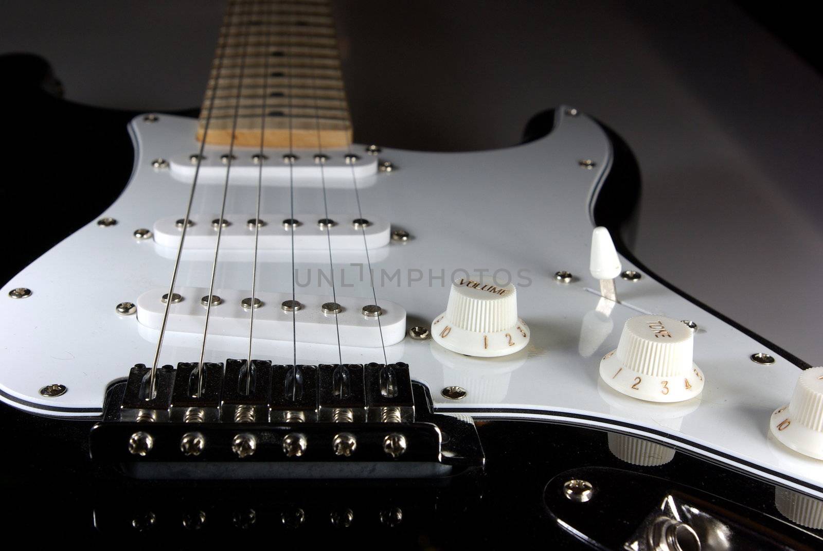 A black and white guitar viewed from the bridge towads the neck of the guitar