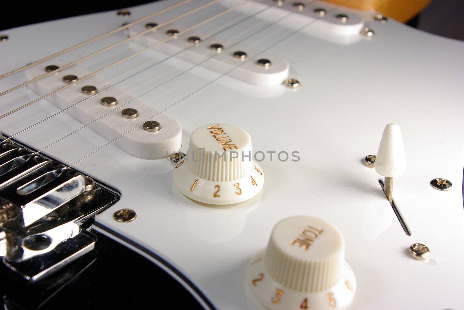 A black and white guitar viewed from the bridge towads the neck of the guitar