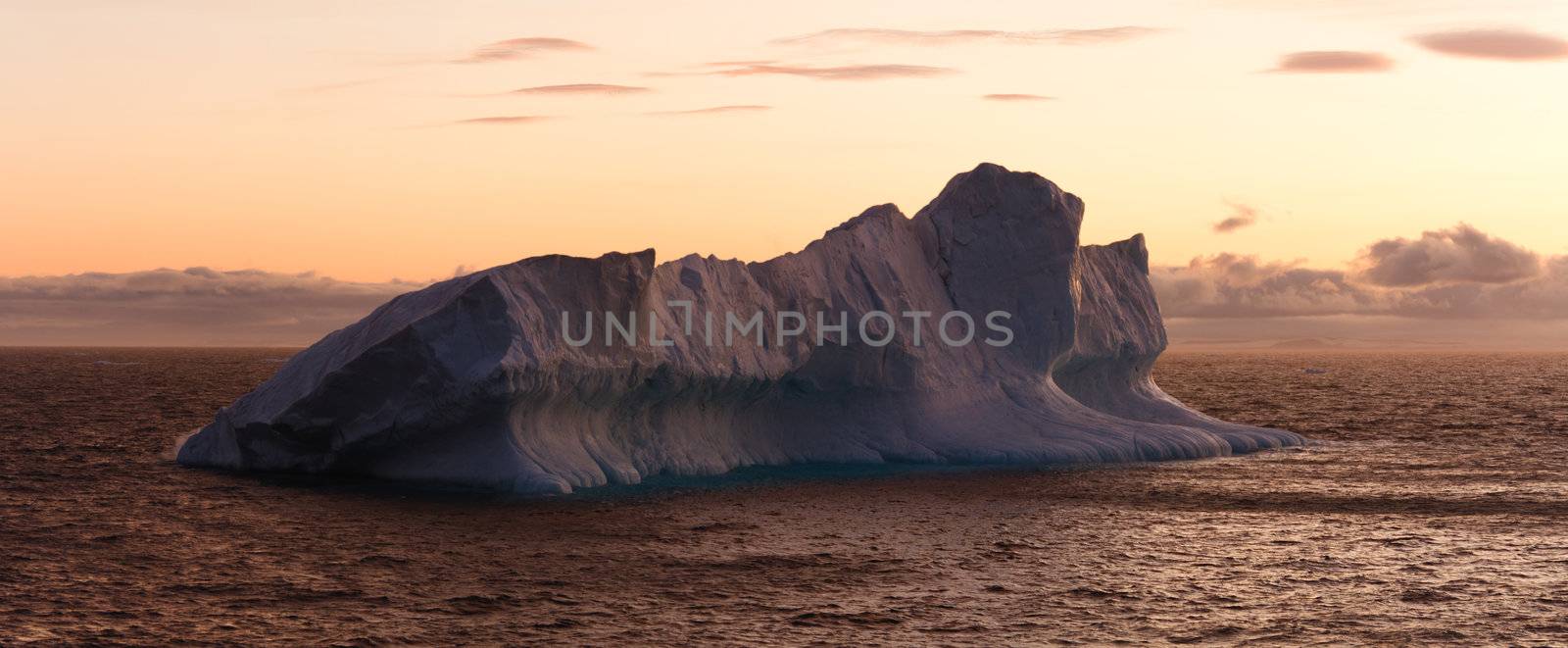 Large iceberg floating in sea at dusk. Horizontally framed shot.