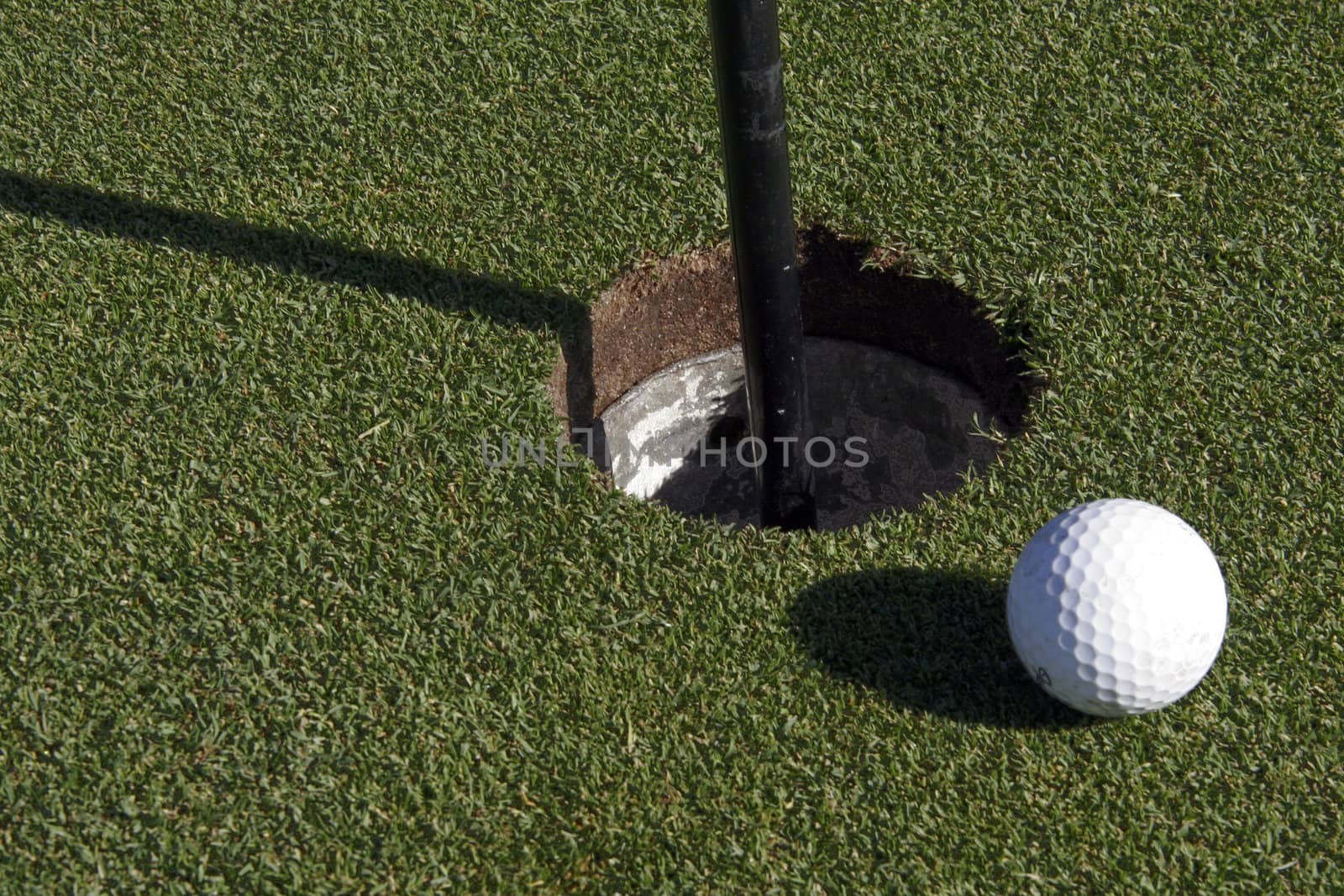 White Small Golf Ball Next To The Hole On The Green