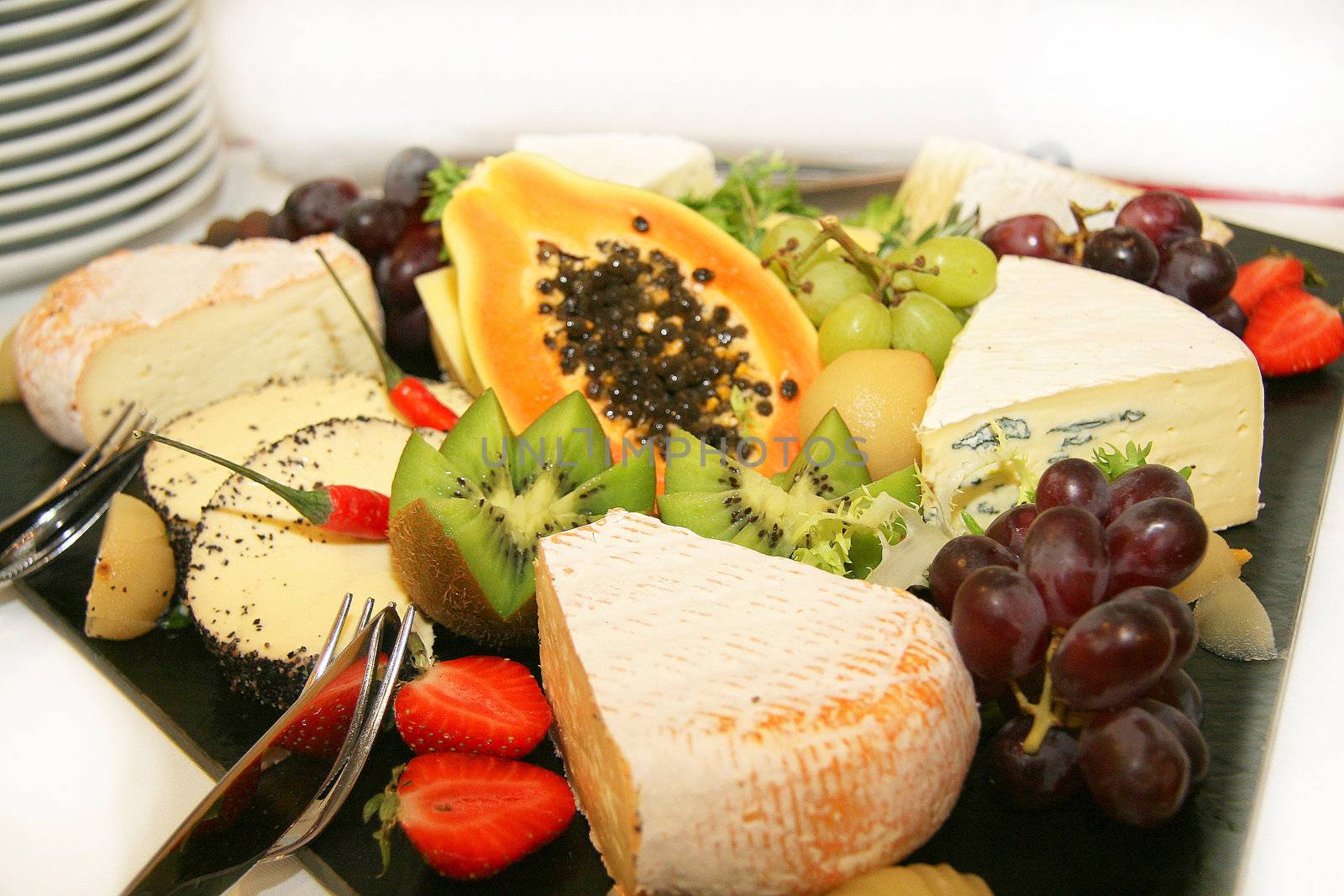 Cheese platter with different types of cheese grapes, kiwi and strawberries