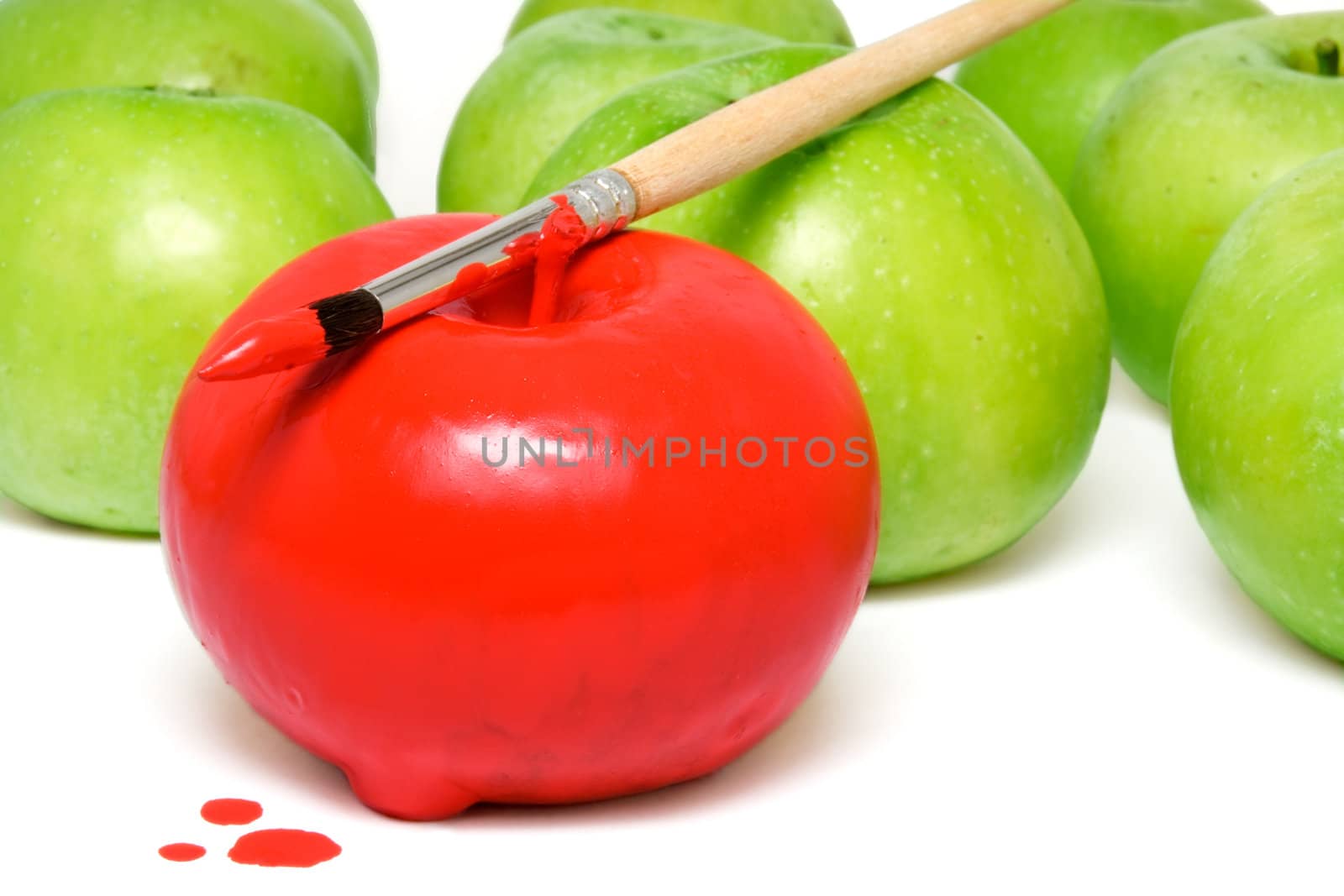 The apple painted by a red paint among unpainted apples