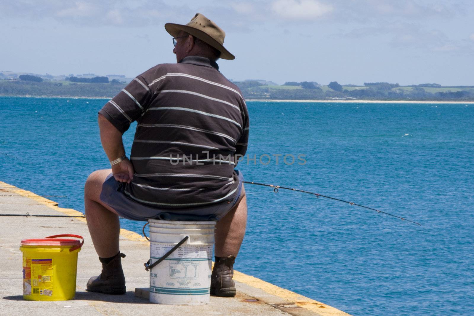 Sunny day in Tasmania's North-West: a lonely fisherman uses his bucket with bait while waiting for the fish to bite.