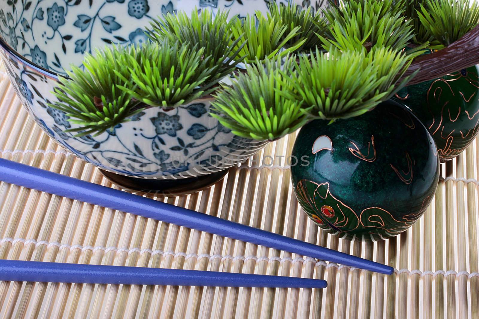 Subjects belonging to east culture: a bamboo laying, a small tree, spheres for meditation, sticks and a deep cup for meal.