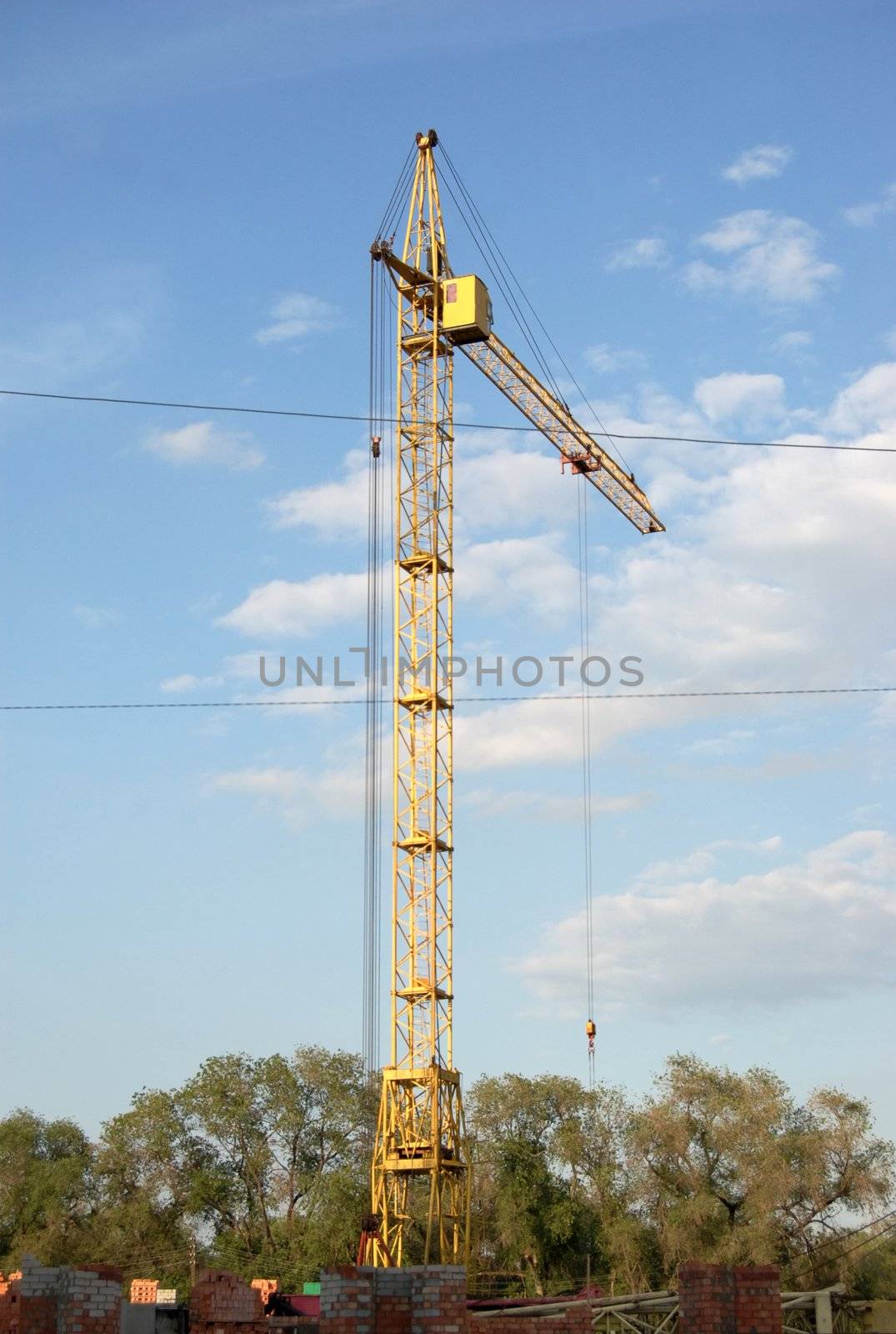 yellow lifting crane over blue sky with clouds