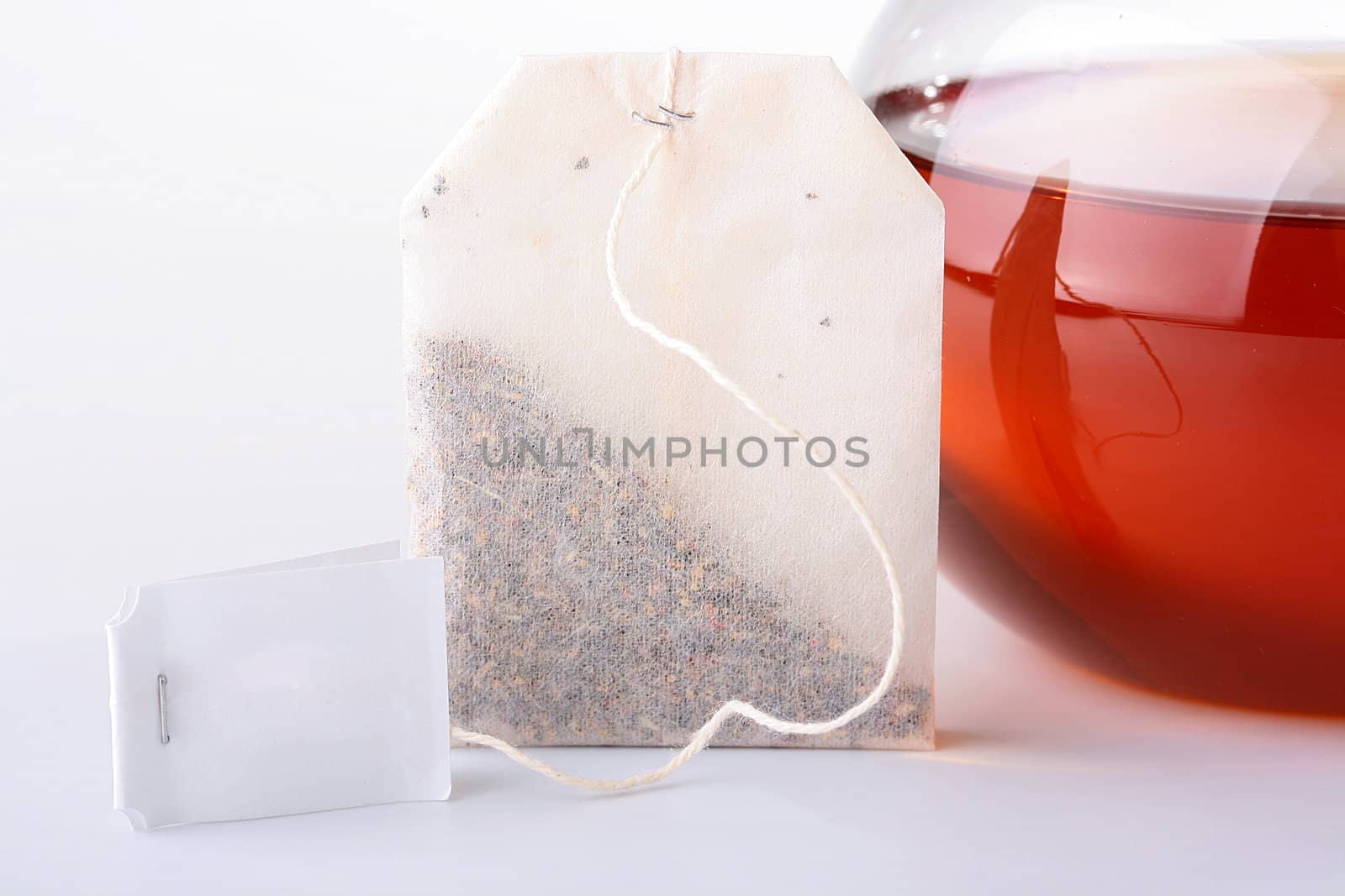 Tea in a paper bag with a pure label against a glass teapot.