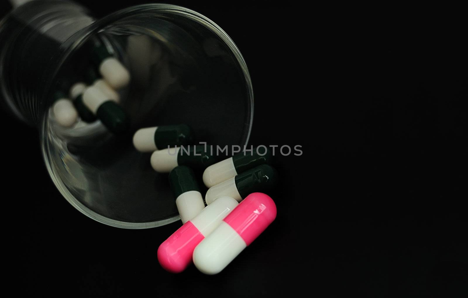 drugs or vitamines? capsules on black in glass