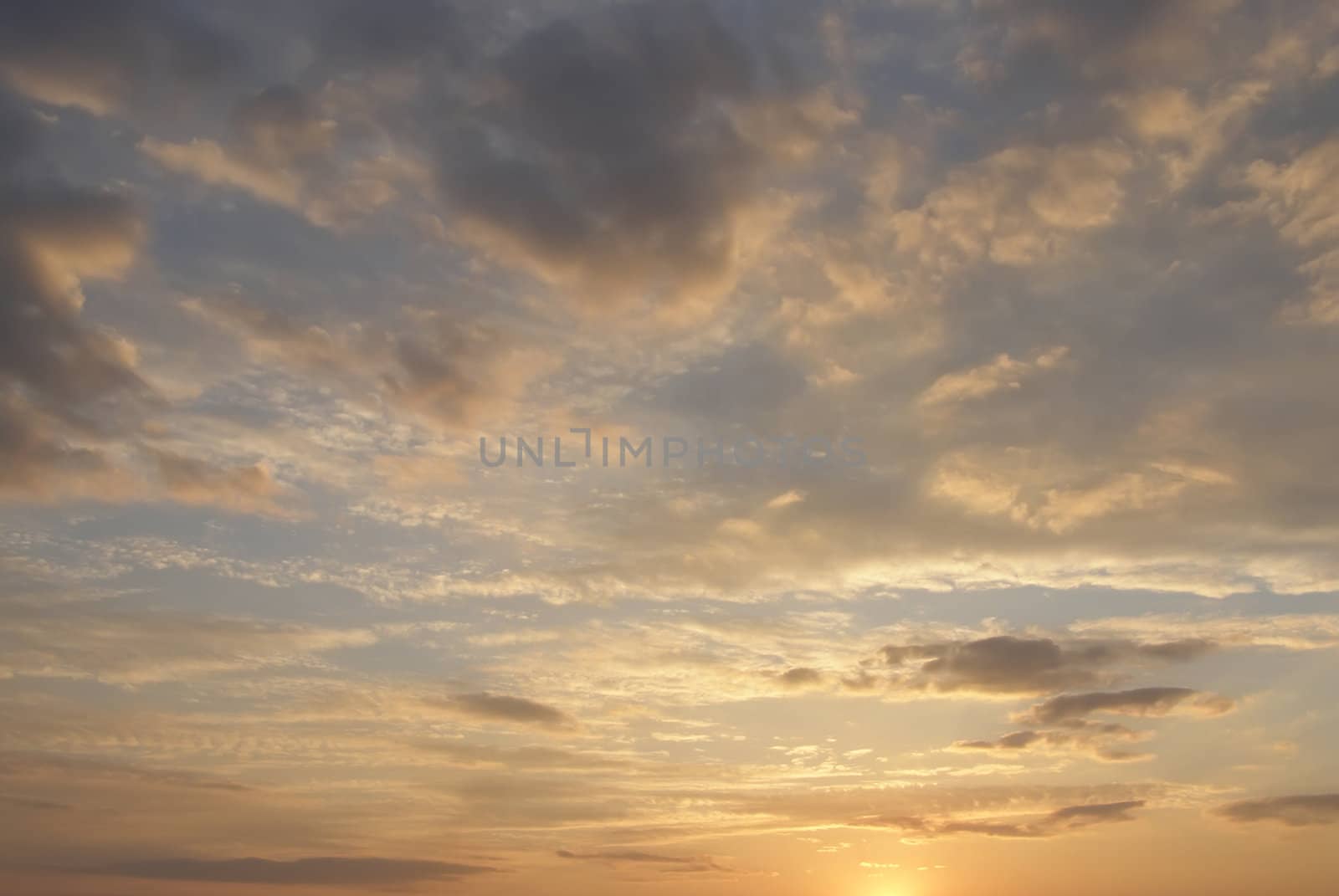 Cloudy sky is in the sunset rays of a sun