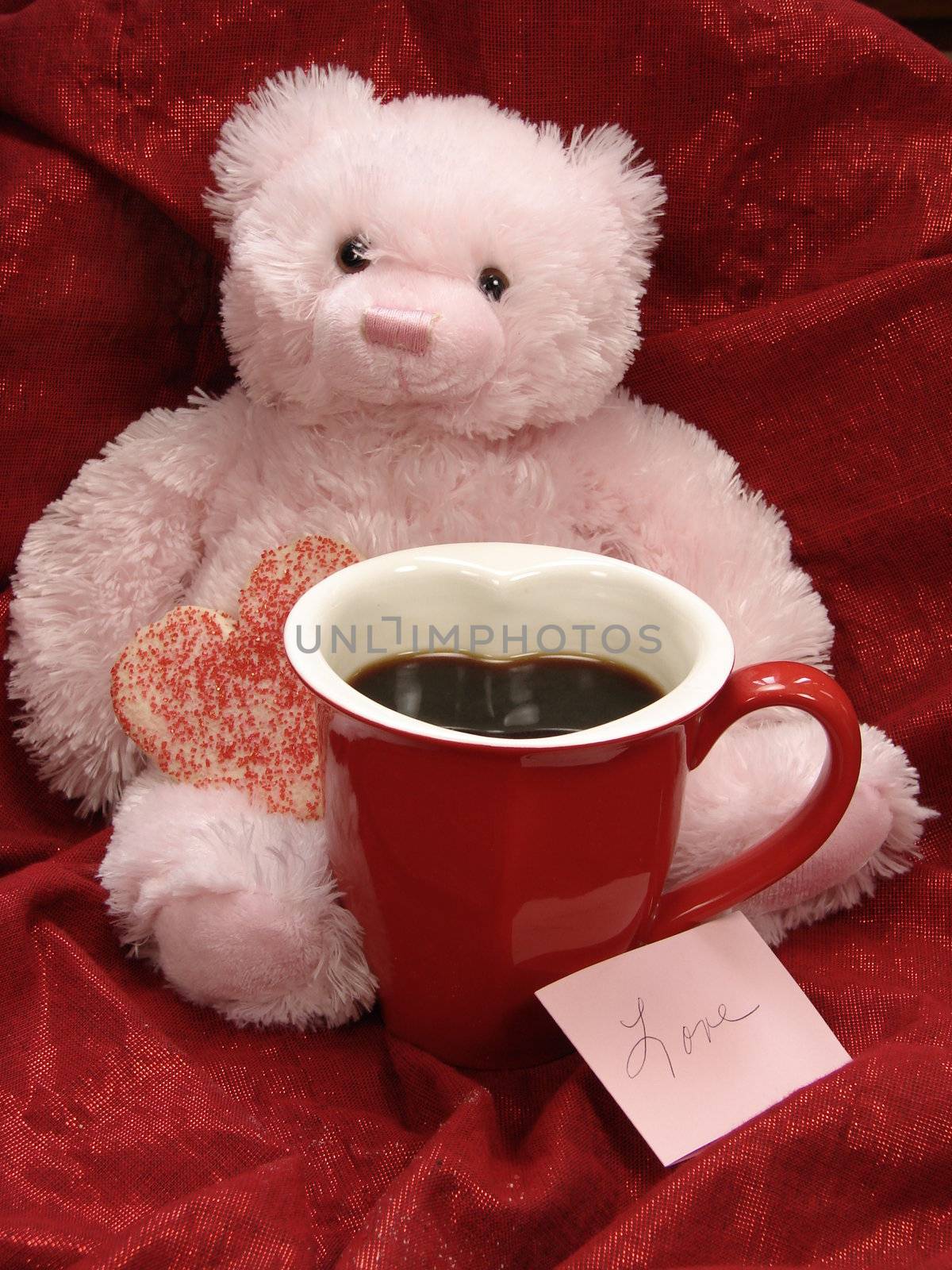 Pink Valentine bear with heart shaped cookie and heart coffee mug. Love Note, Red fabric background.