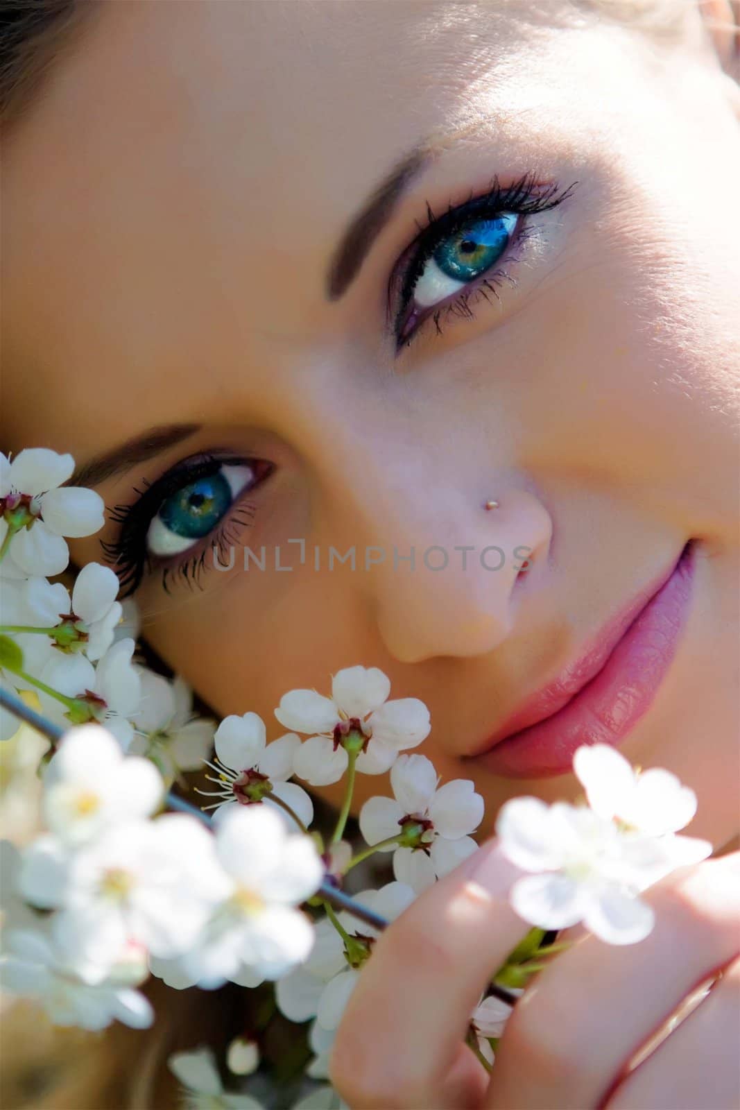 The beautiful girl among flowers in an apple garden