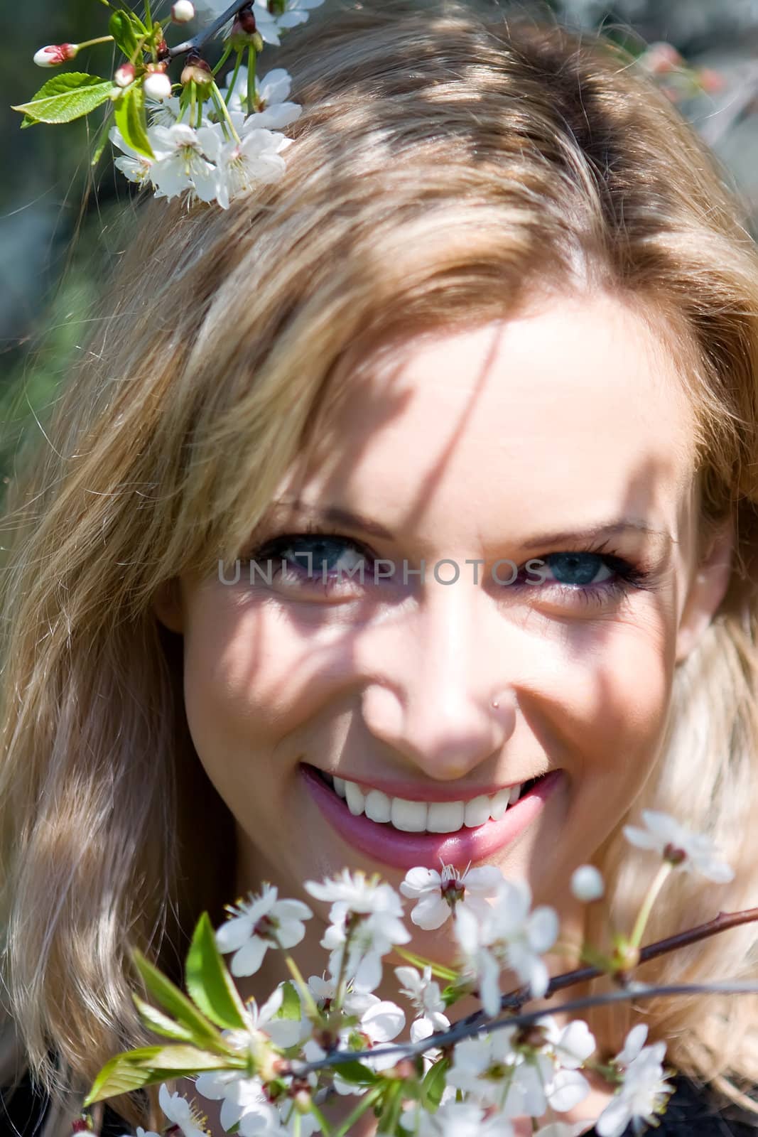 The beautiful girl among flowers in an apple garden