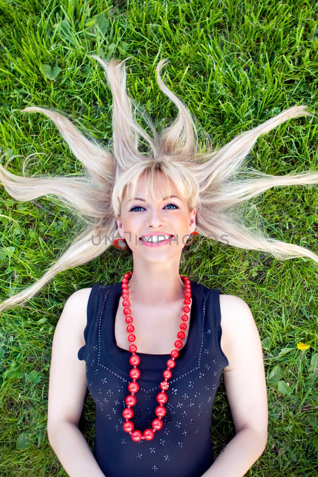 The beautiful blonde laying on a grass with scattered hair