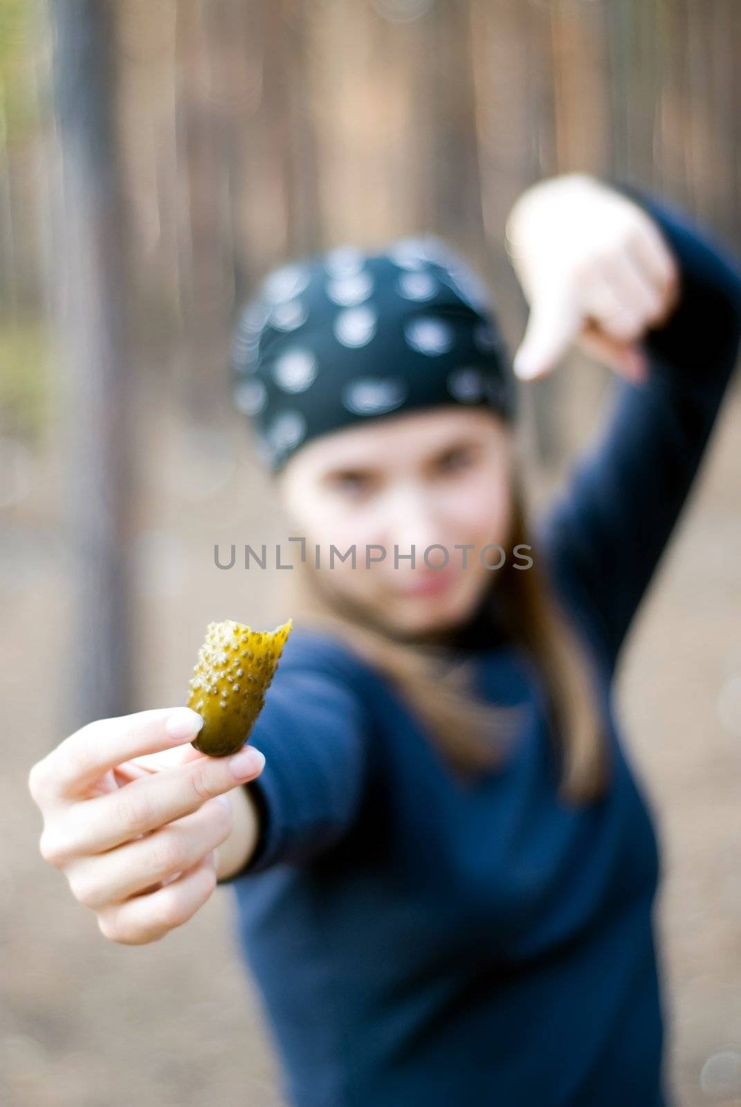 girl in the woods with a cucumber in her right hand. focus on cucumber