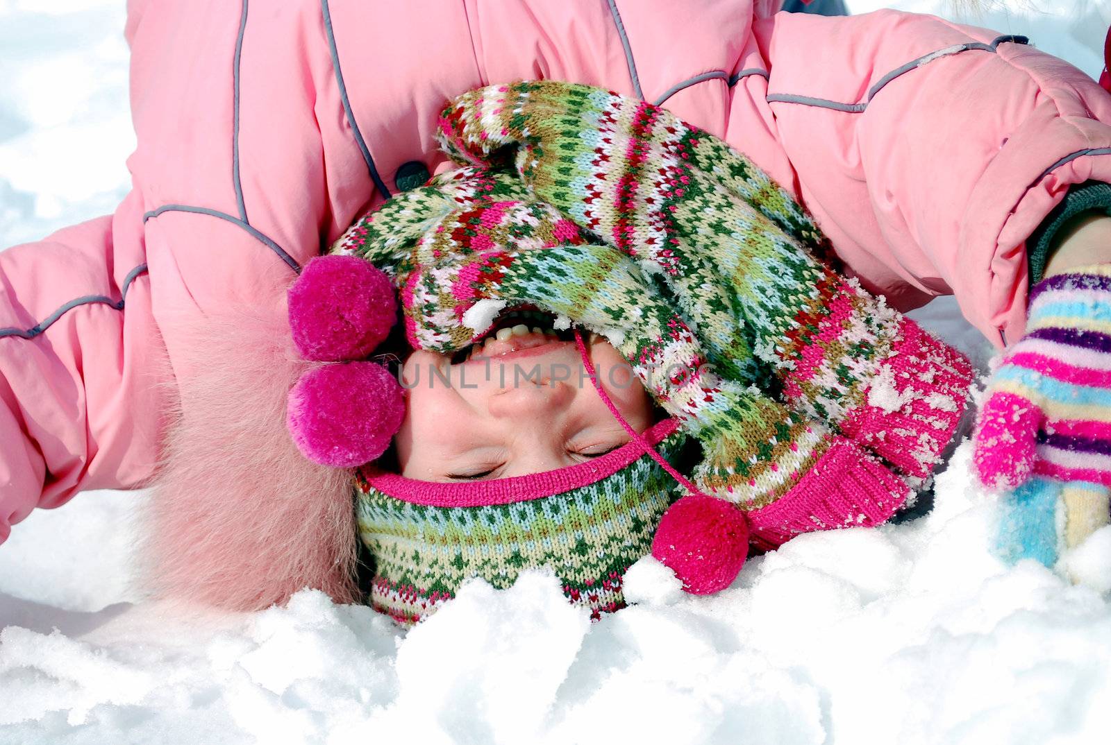 happy little girl in winter clothing standing upside down in the snow