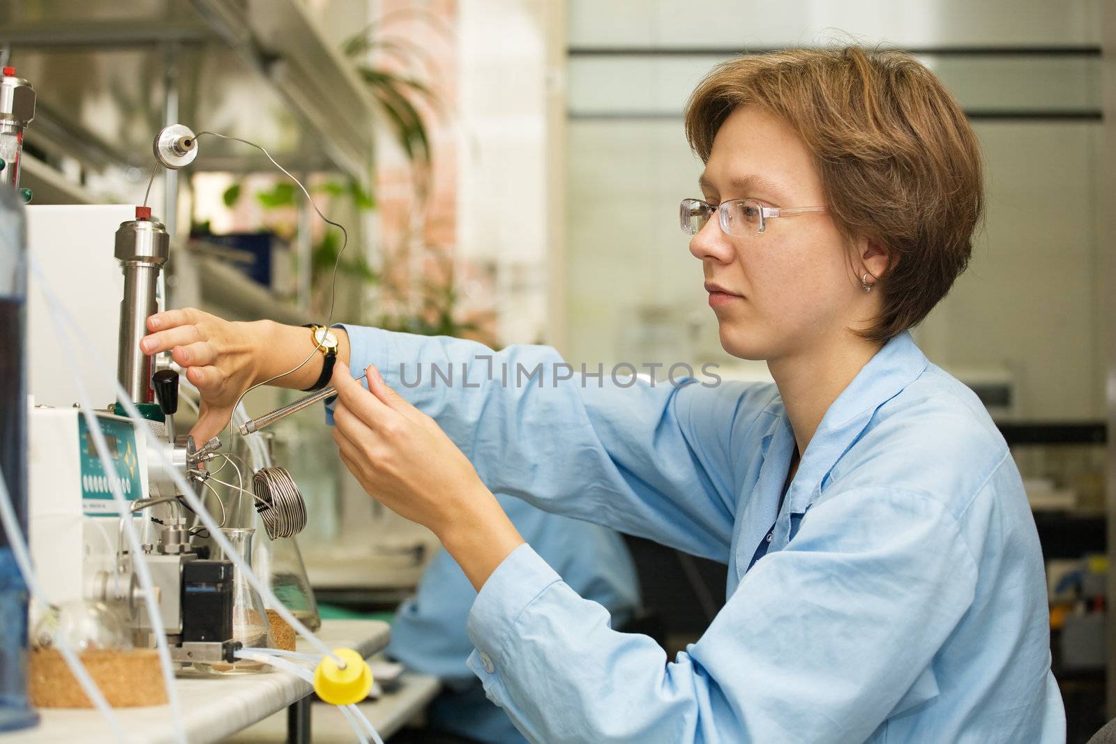 The young nice woman-scientist work with syringe on a background scientific instruments