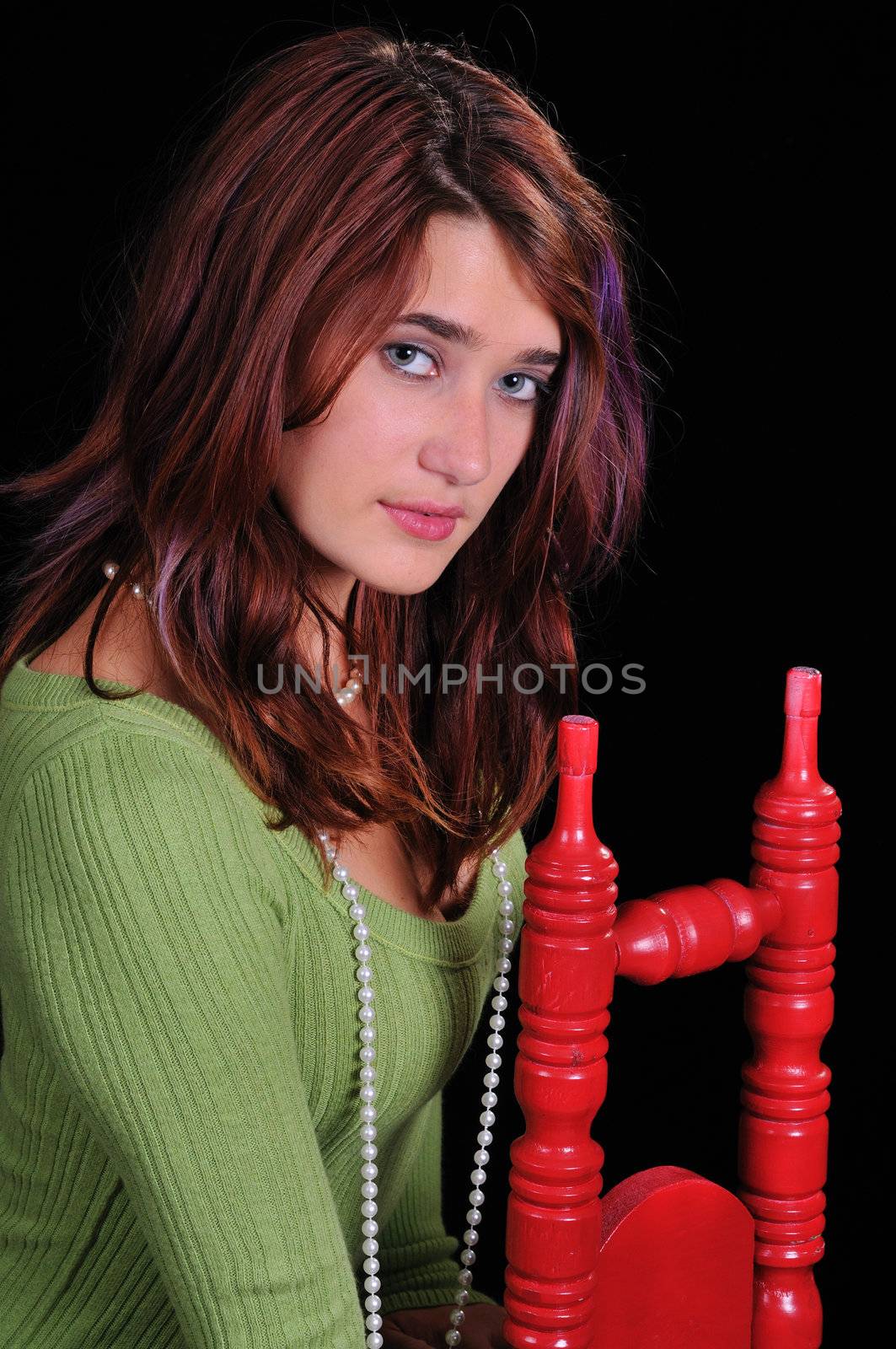 Attractive young woman in a tall back chair on a black background