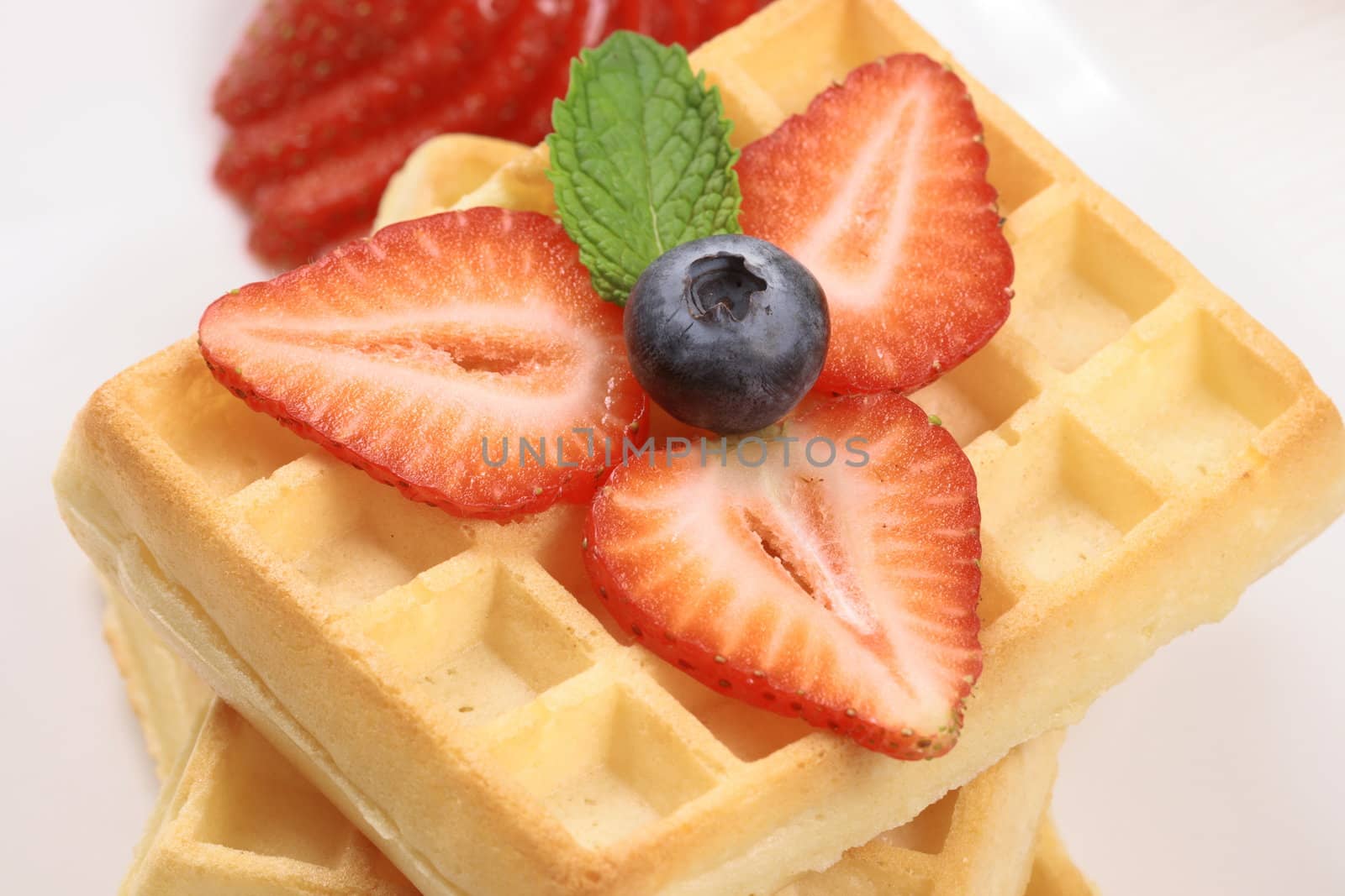 Exquisite belgian waffle garnished with organic strawberry and blueberry
