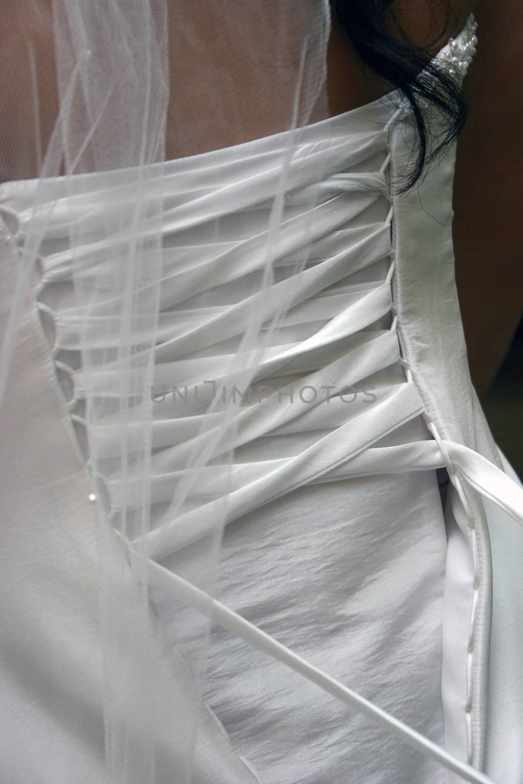 The back of a bride's wedding dress while she is getting tied up.