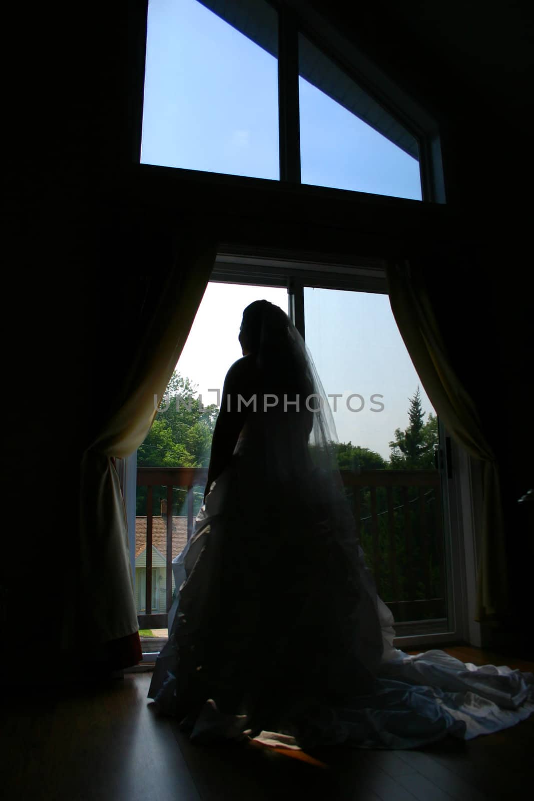A bride eagerly pondering her wedding day at the front window.