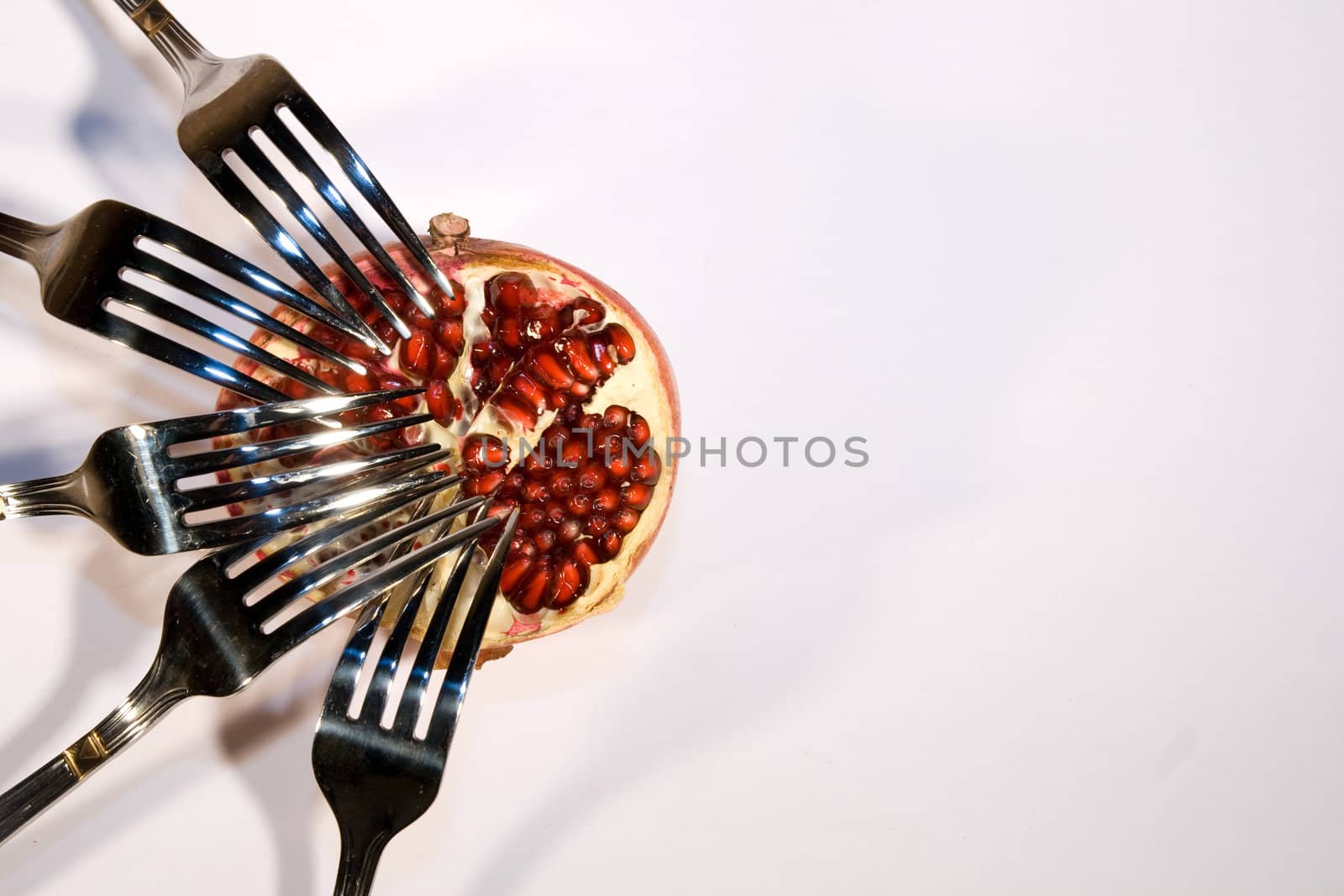 Red pomegranate with metal plugs in a white environment