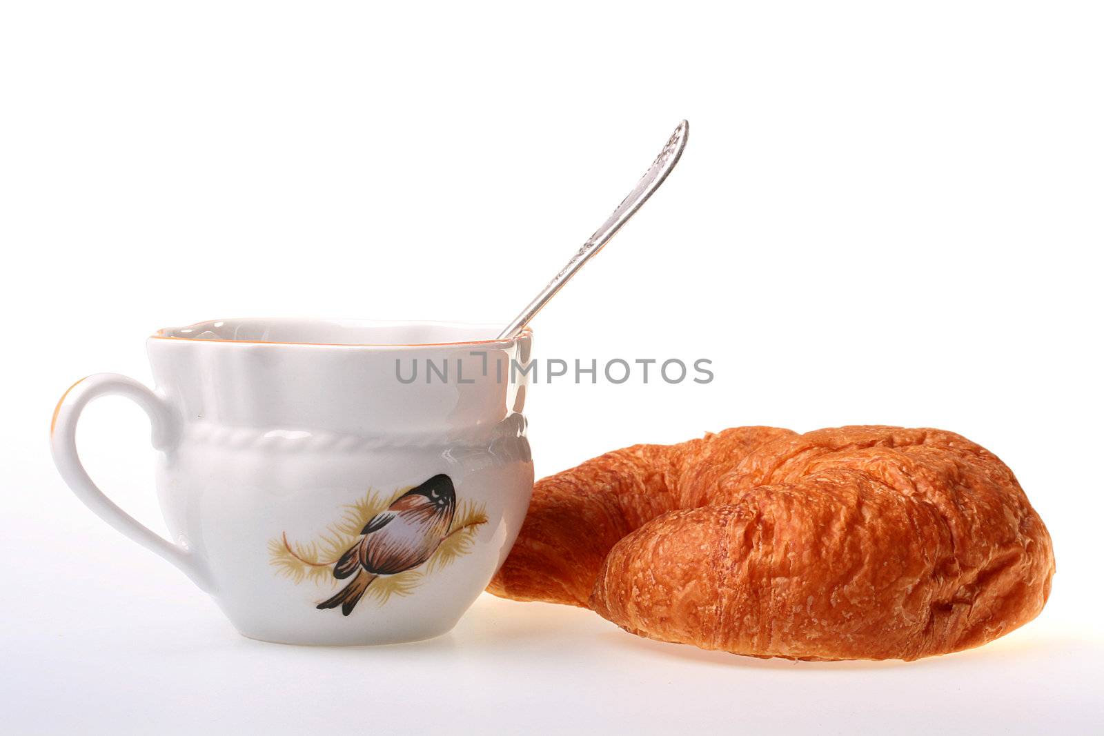 Cornetto and a cup with tea in a cup a teaspoon.