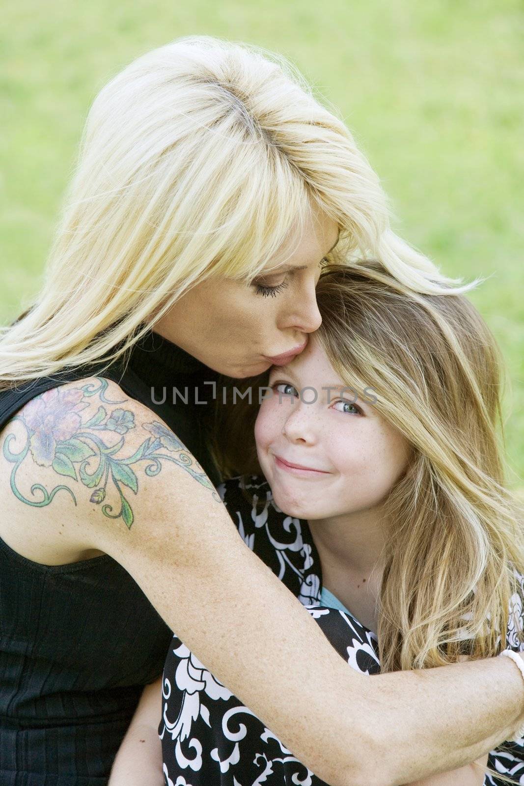 Pretty mom hugs and kisses her cute freckle-faced daughter