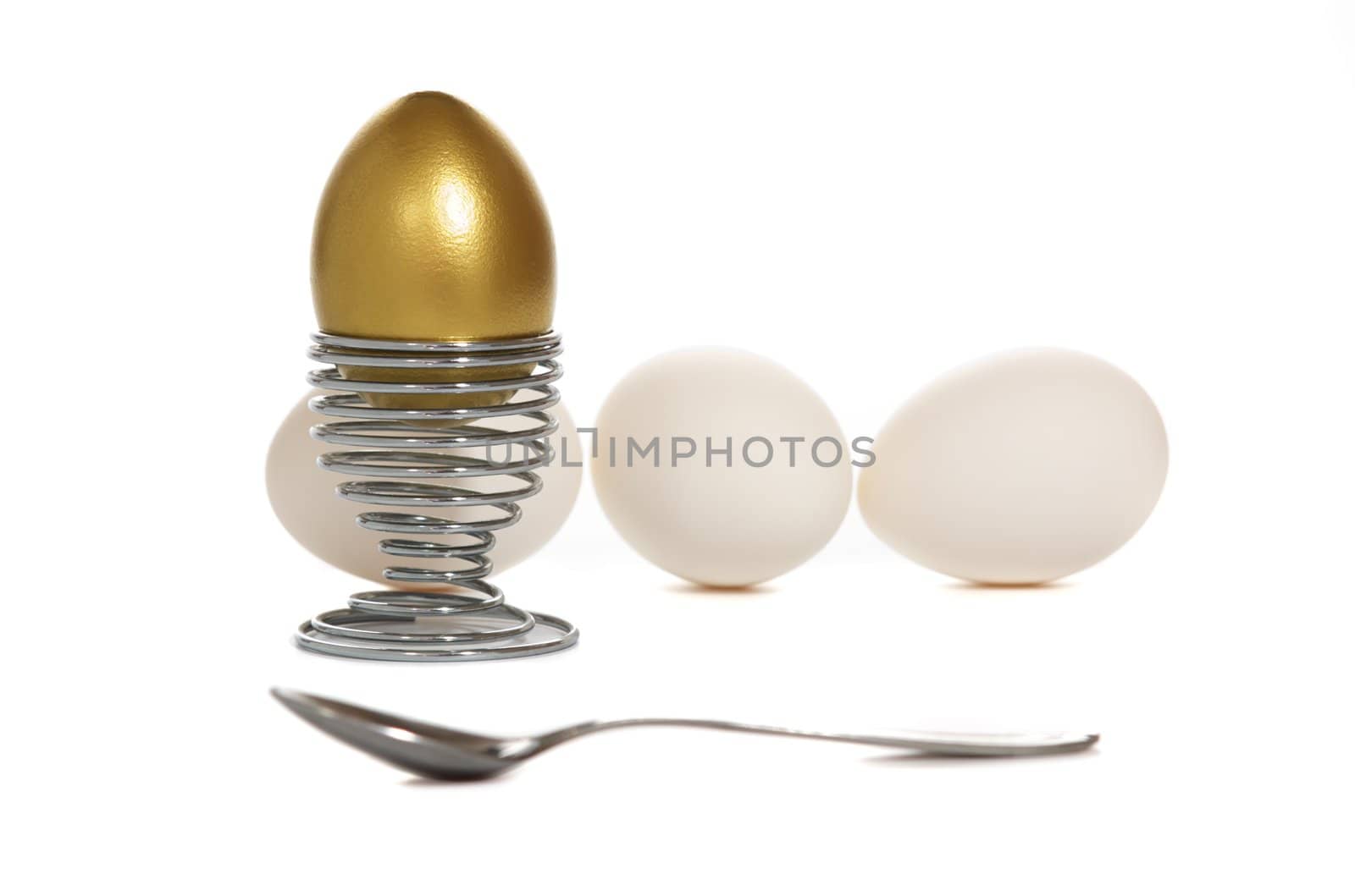 golden egg on iron stand near by white eggs with iron spoon isolated on white background