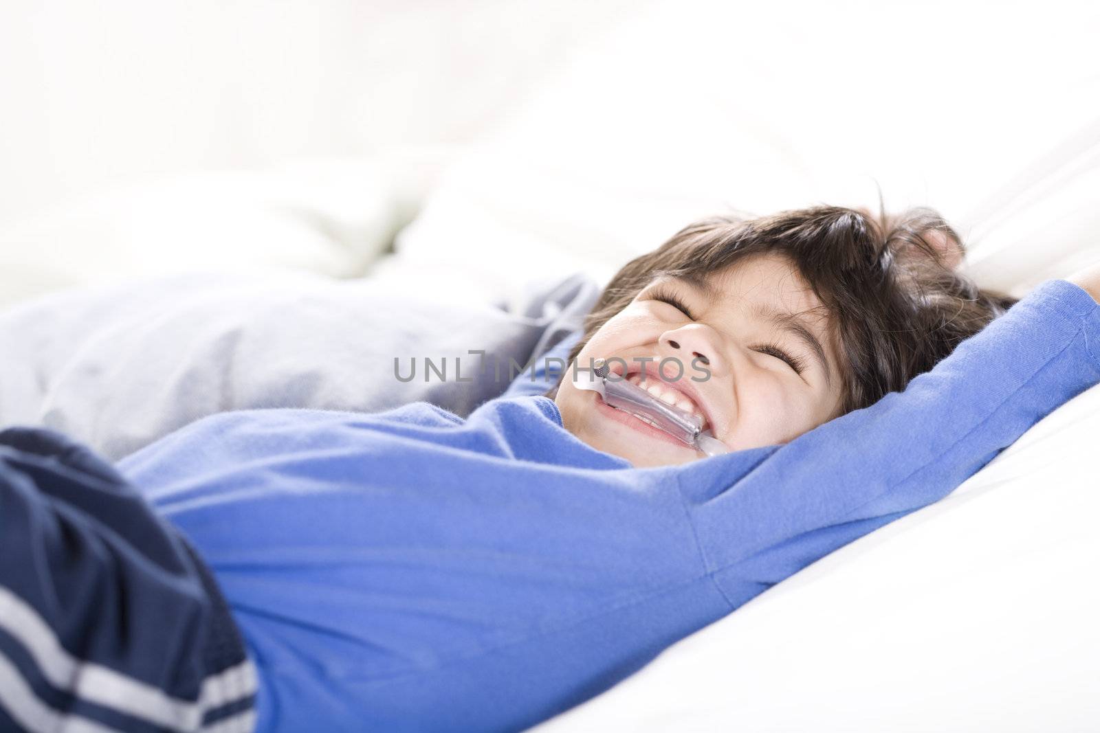 Disabled boy stretching happily on bed