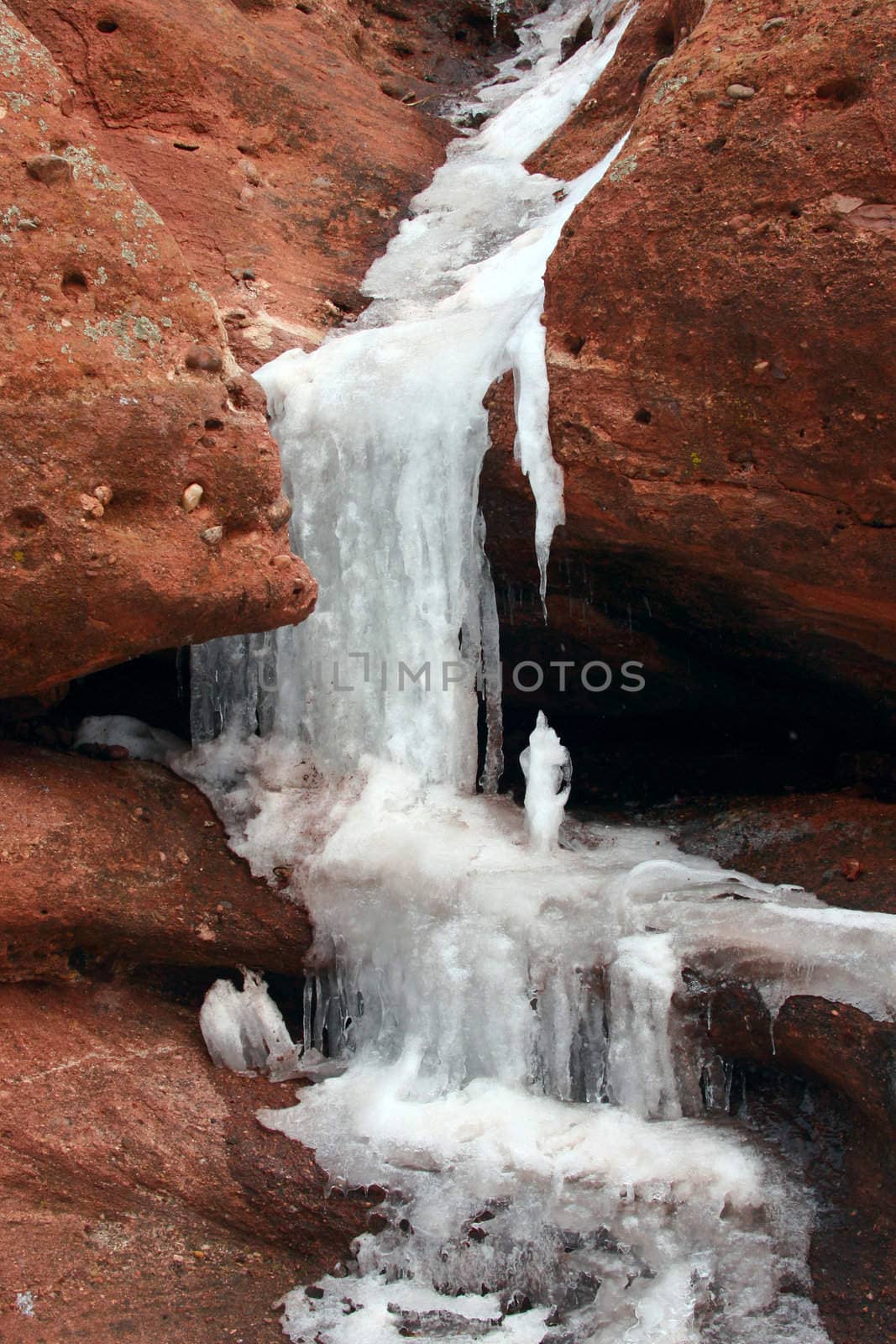 Waterfall frozen in the middle of winter creating icy stalactites and stalagmites.