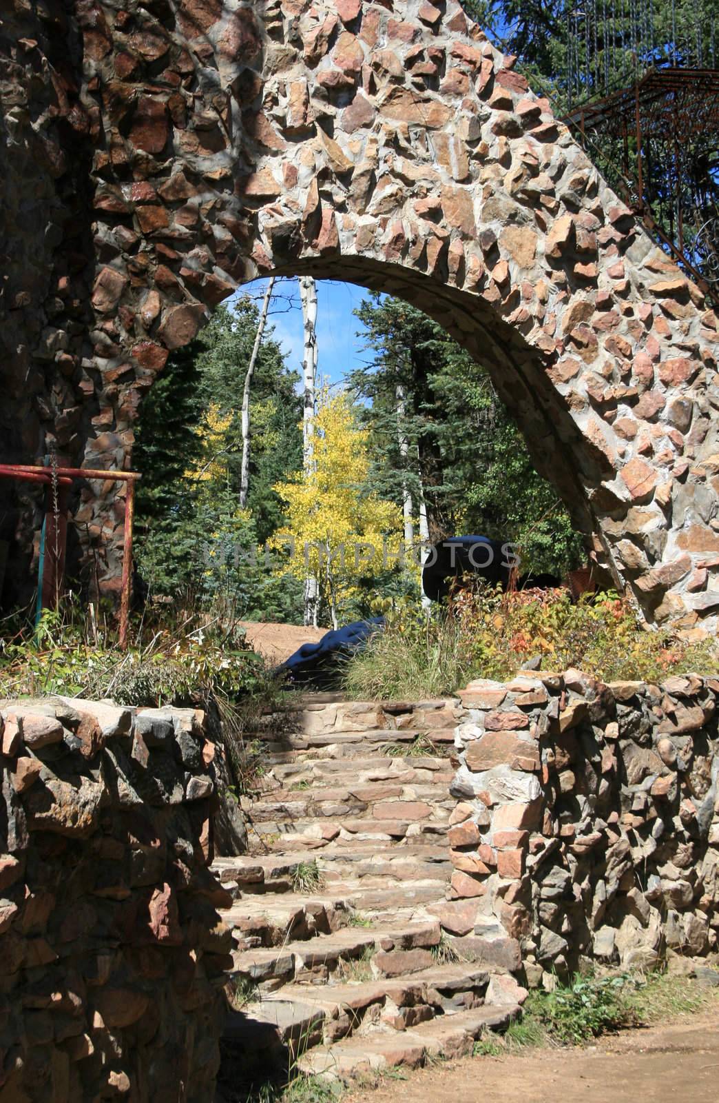 A single golden-leafed aspen tree is outlined by the hand-hewn stone archway of a unique castle in the Colorado Rocky Mountains