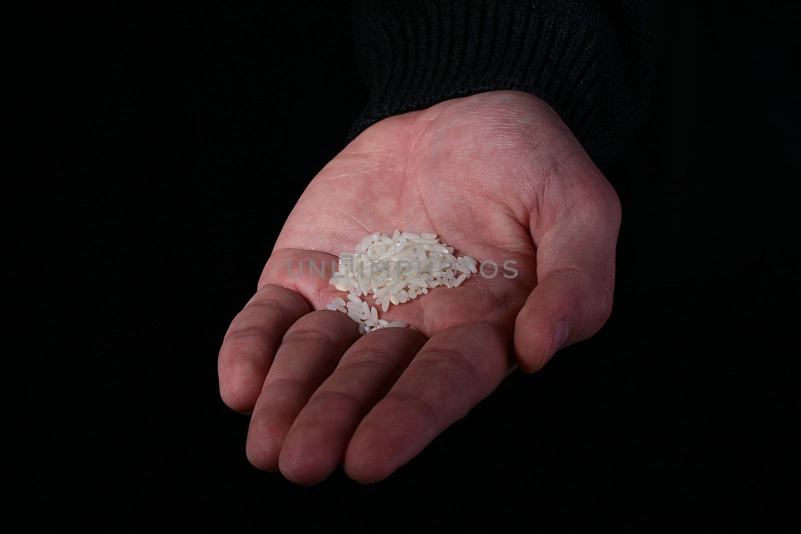 Man is hand with a small handful of rice on a black background.