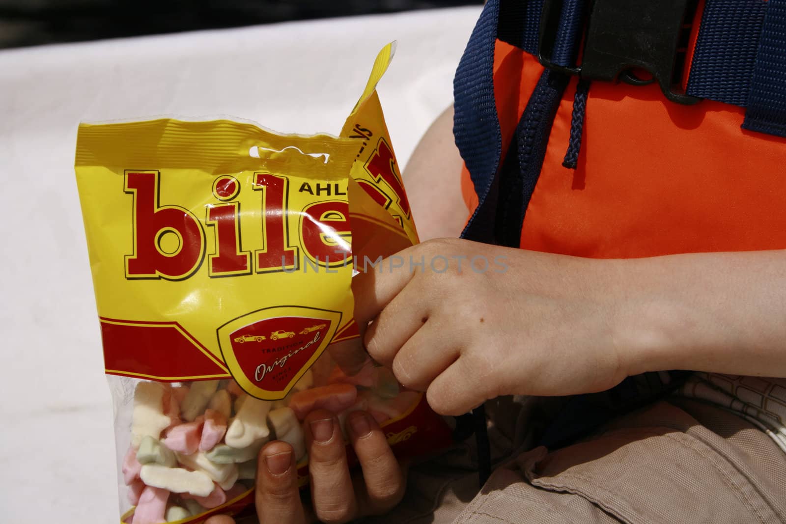 swedish candy called biler (cars). very popular with the kids. here depicted in the hand of a child on a boat trip. the child is wearing a life vest.