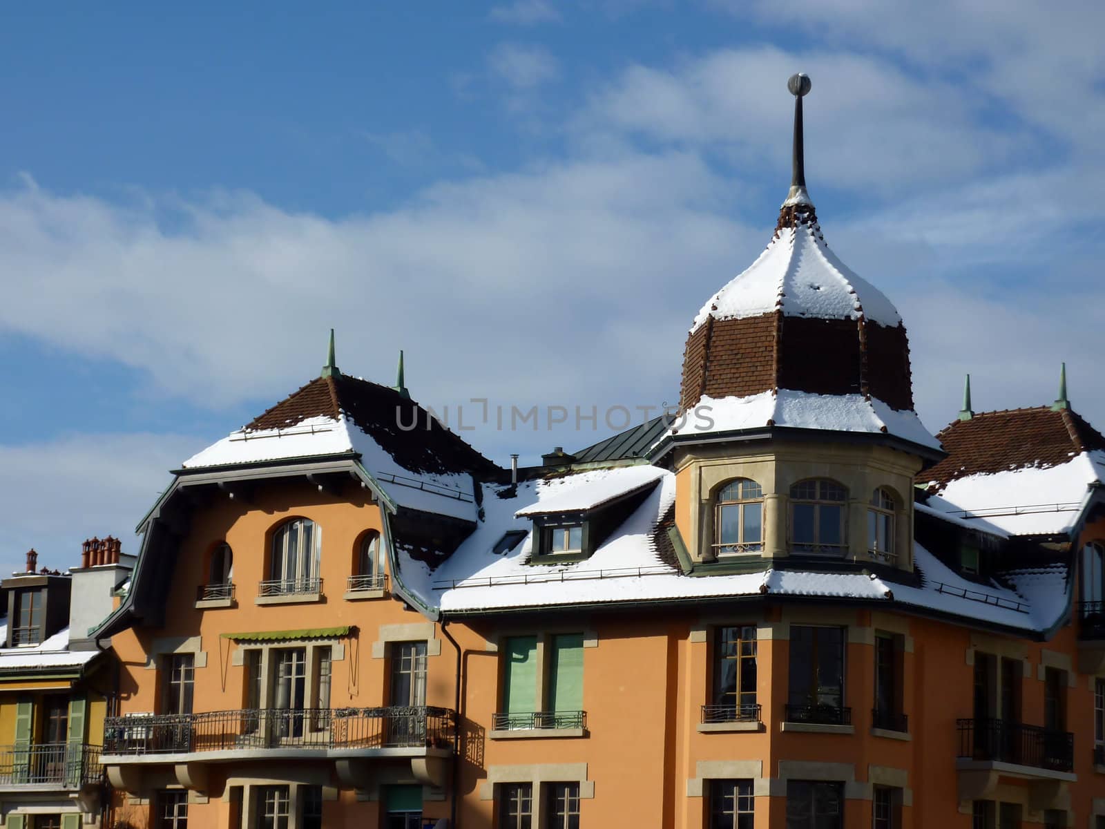 Snow on roof of a colored building by sunny day