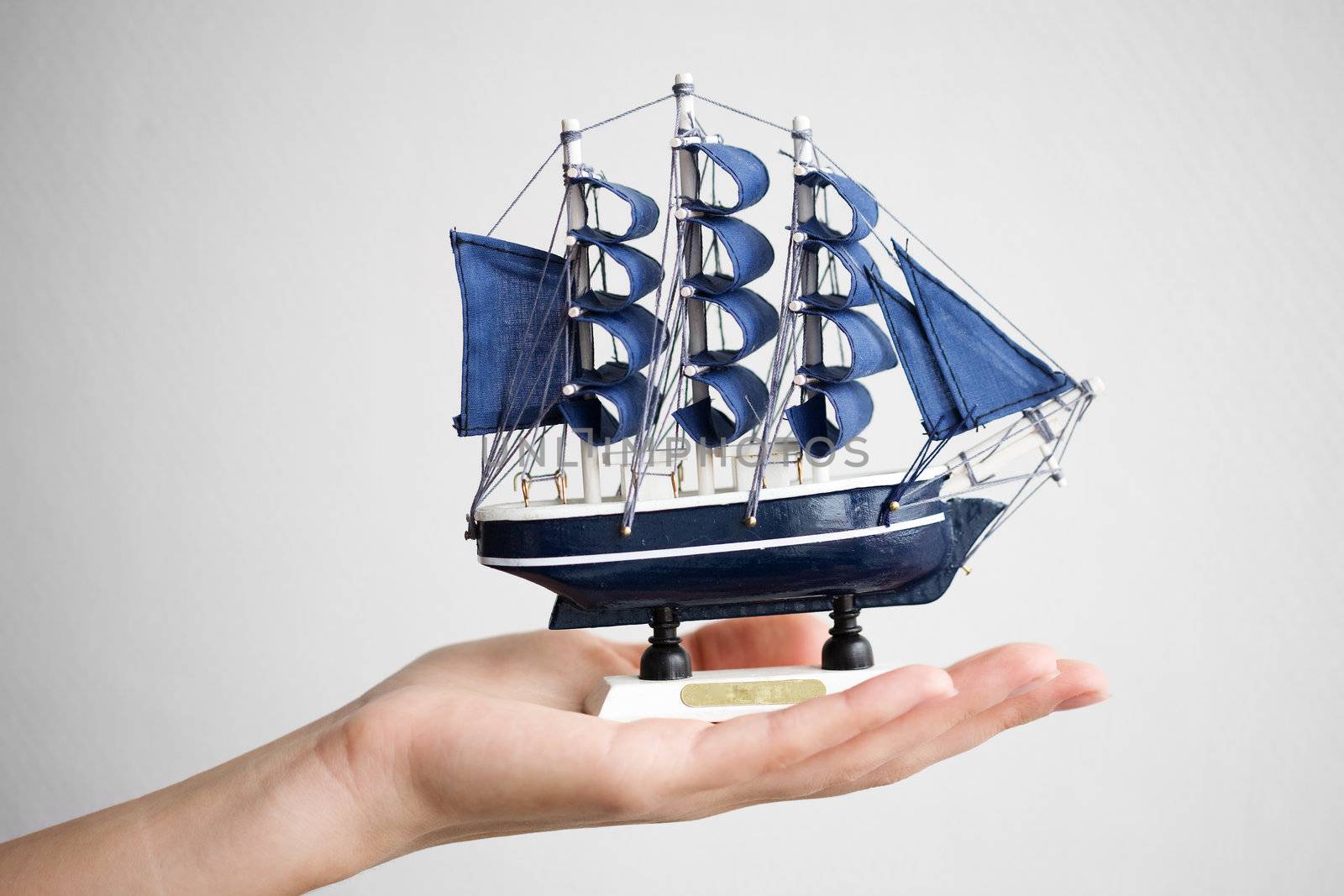 The hand holds a small ship. 