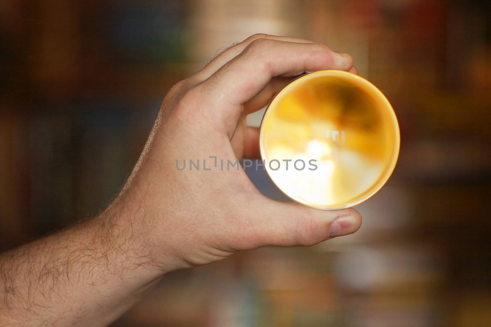 Abstraction. The glass yellow sphere in a palm. Shallow depth of field. 