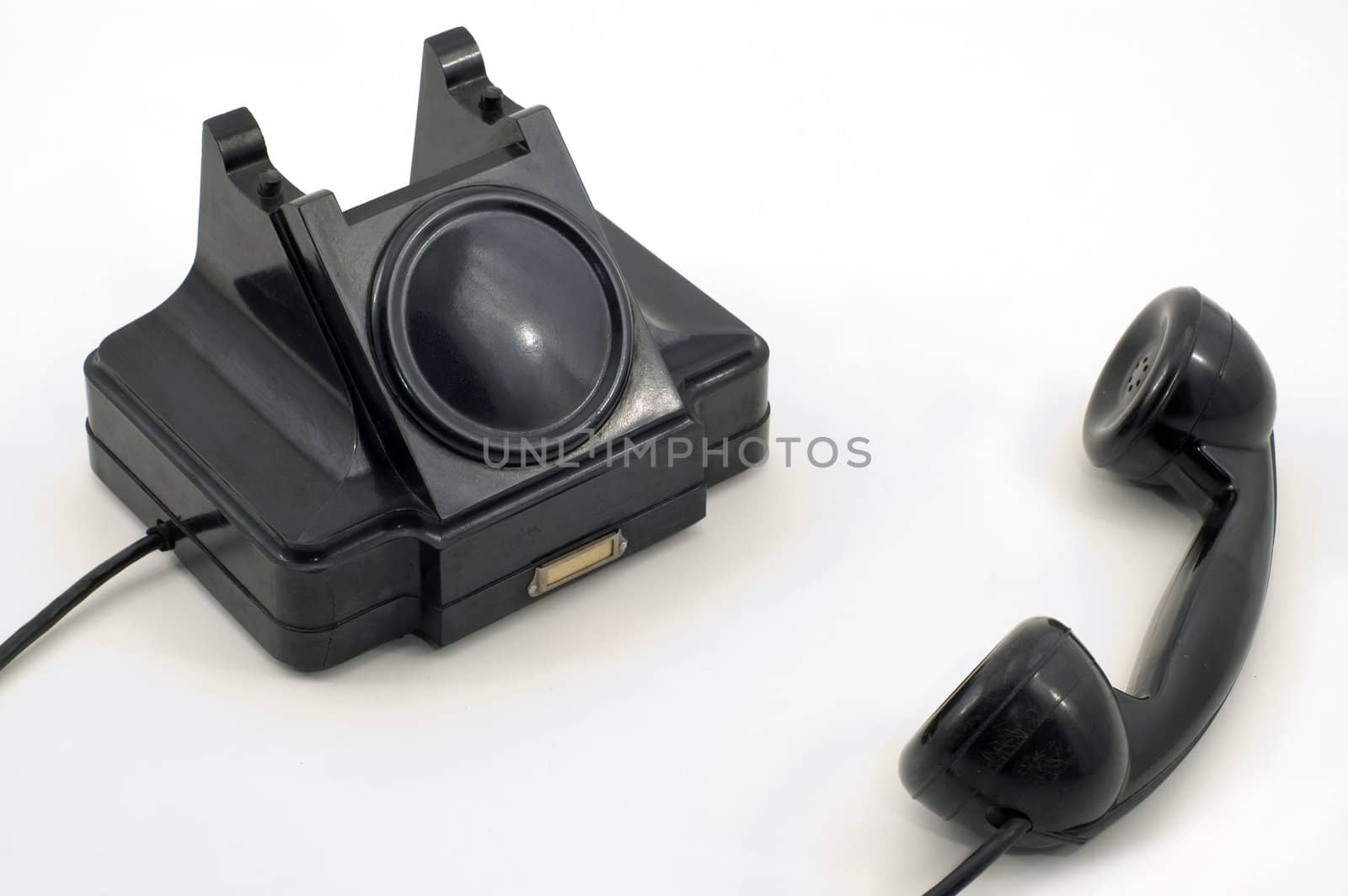 Old-fashioned black telephone receiver with cord on white background.