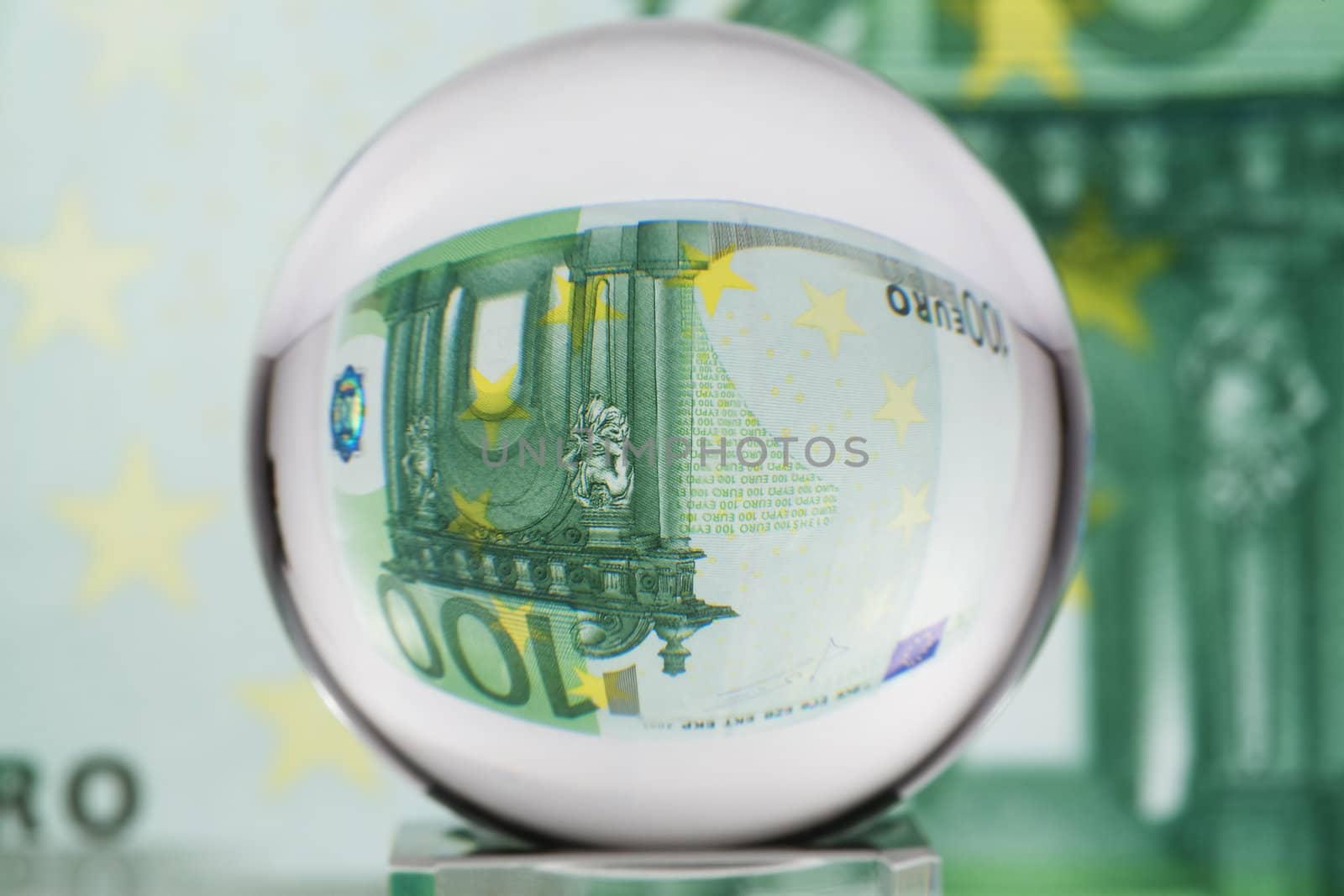 Hundred euro banknote through glass sphere. Blur background.