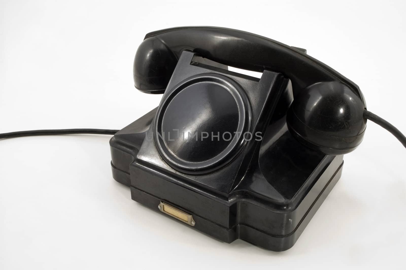 Old-fashioned black telephone receiver with cord on white background