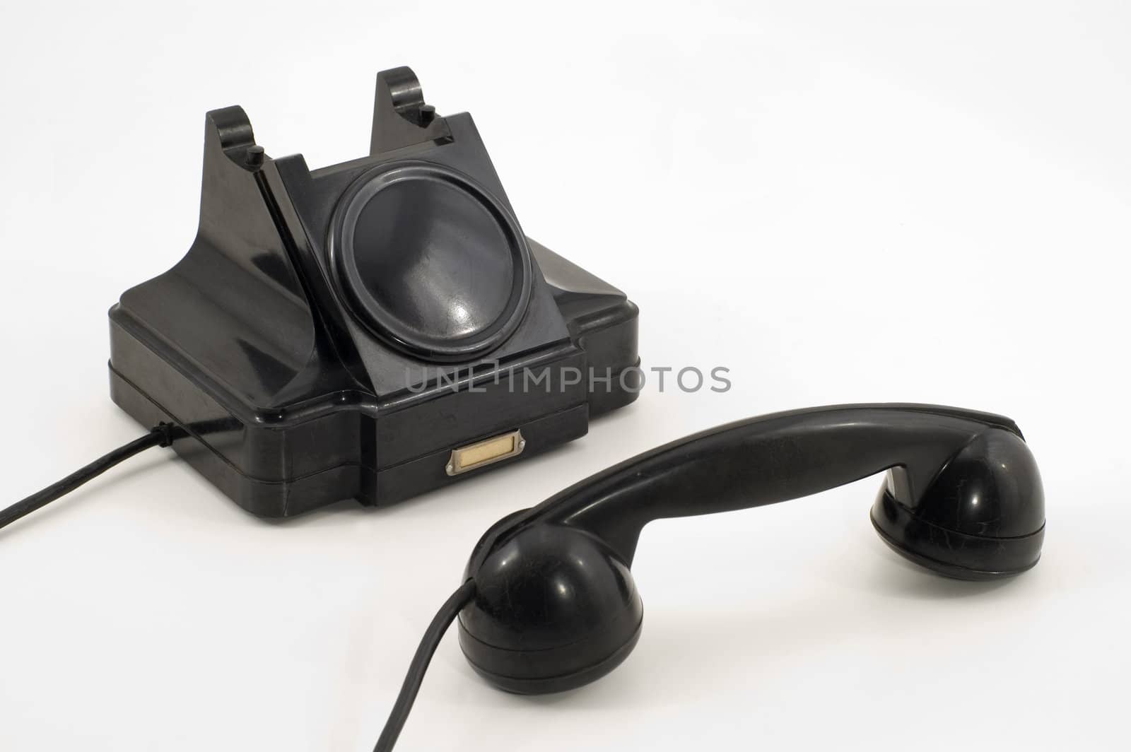 Old-fashioned black telephone receiver with cord on white background.
