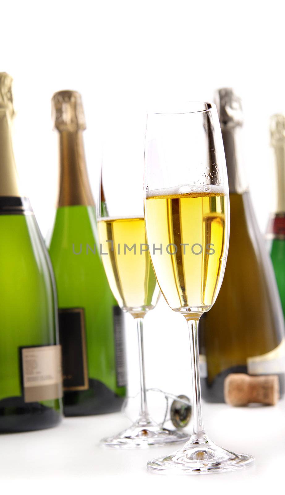 Glasses of champagne with bottles on white background
