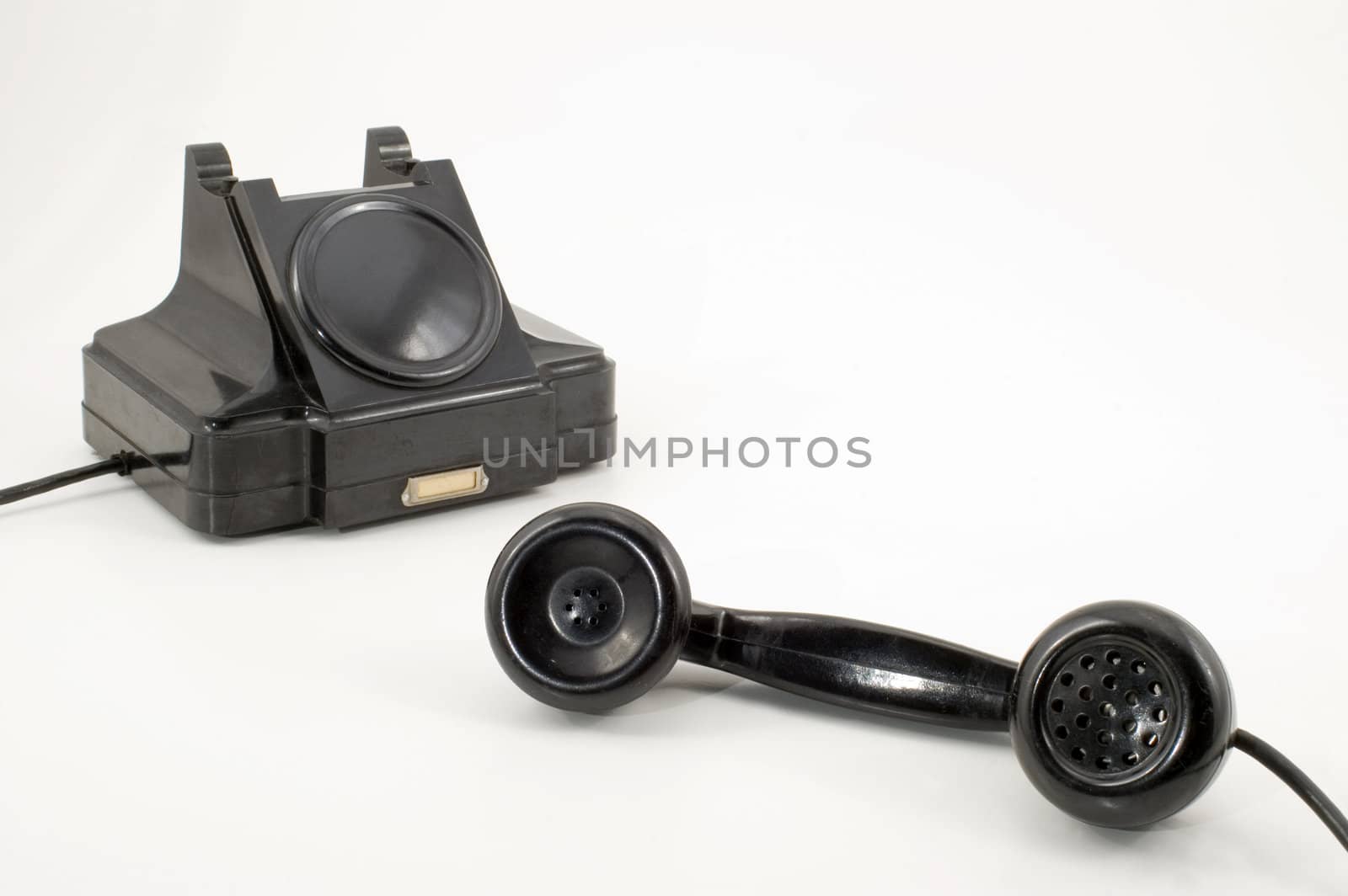 Old-fashioned black telephone receiver with cord on white background.