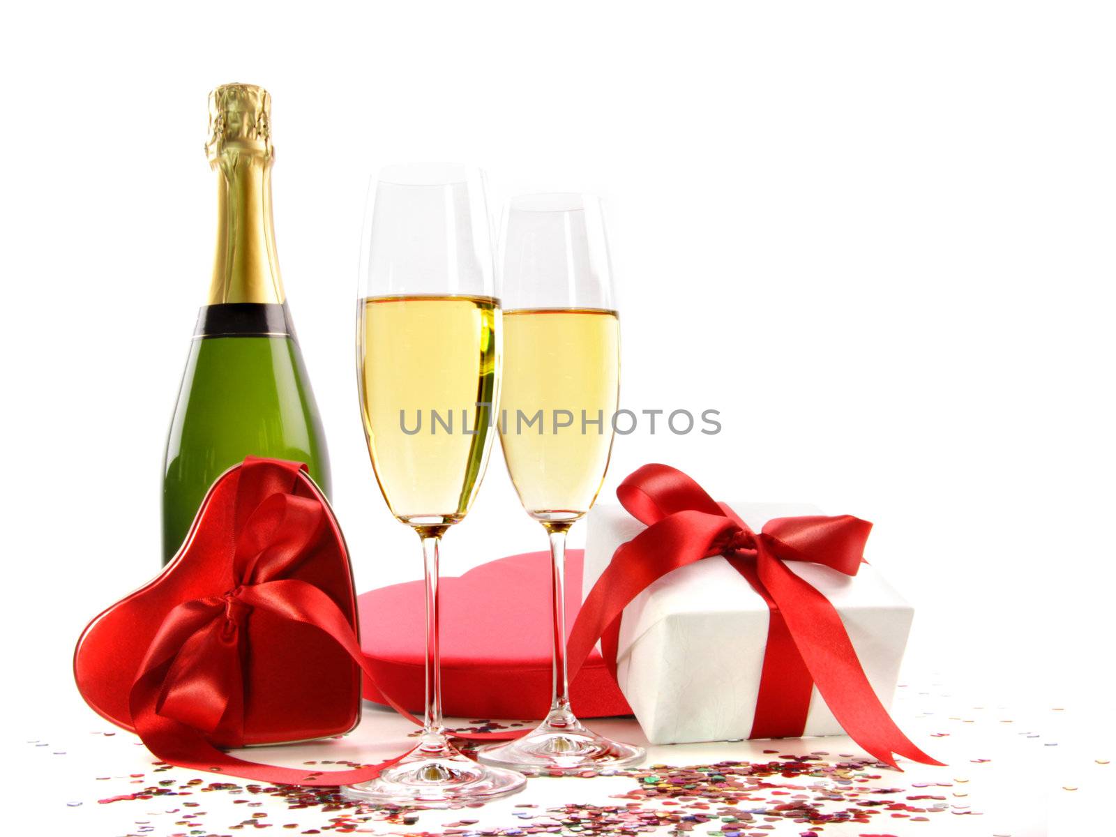 Glasses of champagne with bottle and gifts on white