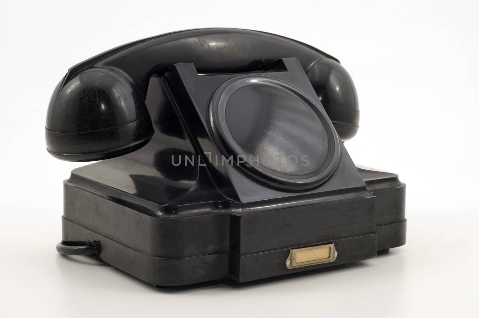 Old-fashioned black telephone receiver with cord on white background.