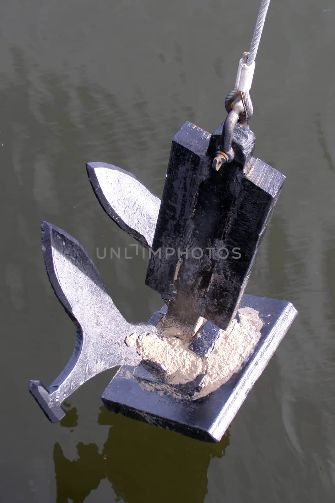 heavy black anchor fastened on a rope overwater  