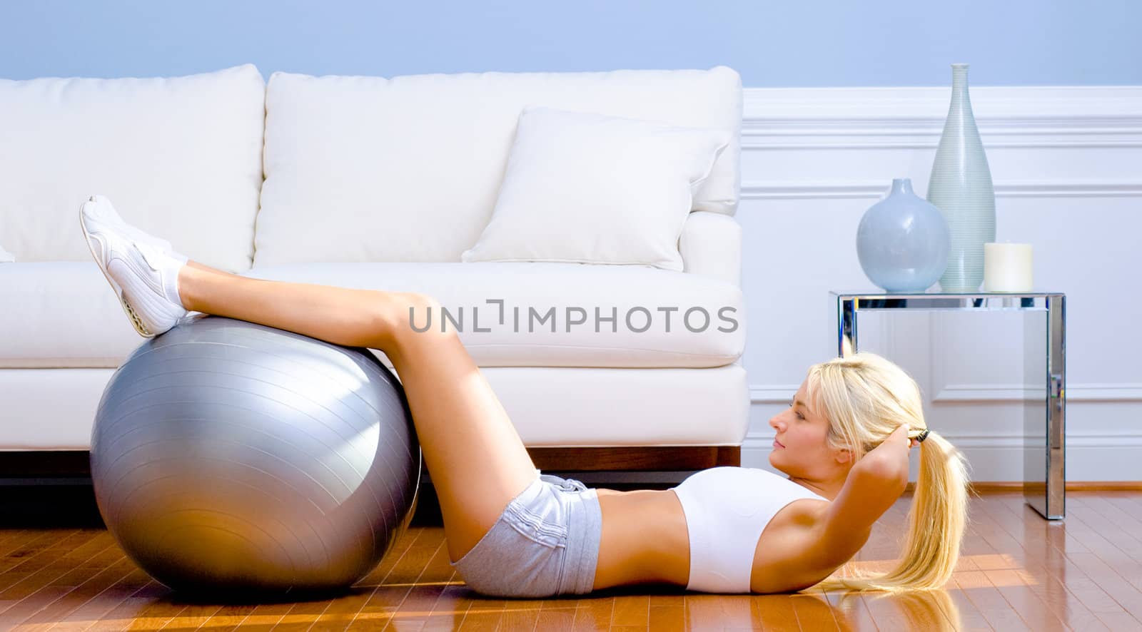 Side view of young woman in sportswear doing crunches in a living room.  Horizontal shot.