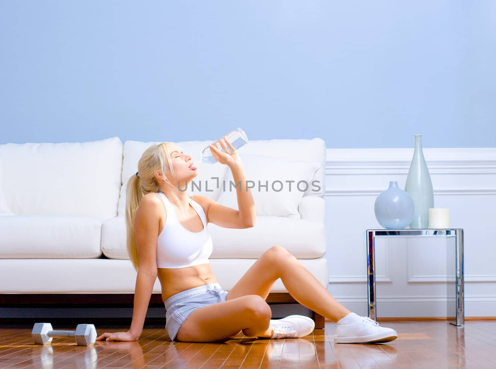 Side view of a young woman drinking bottled water after exercising.  Horizontal shot.