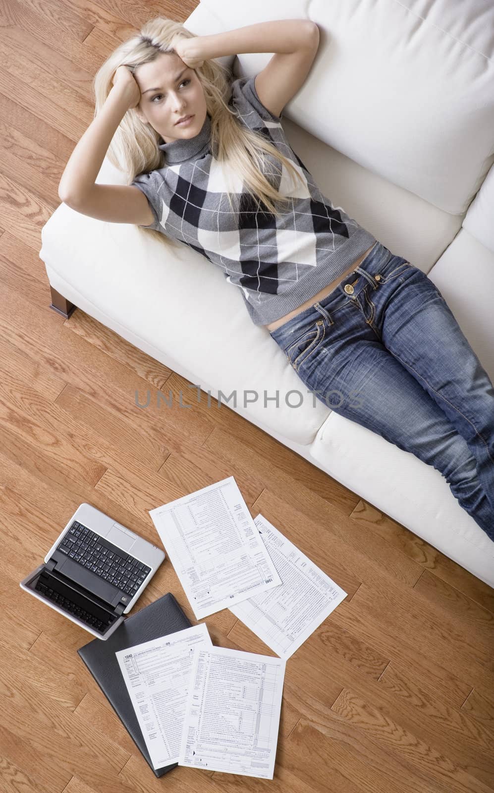 High angle view of a young woman frustrated while doing paperwork. Vertical shot.